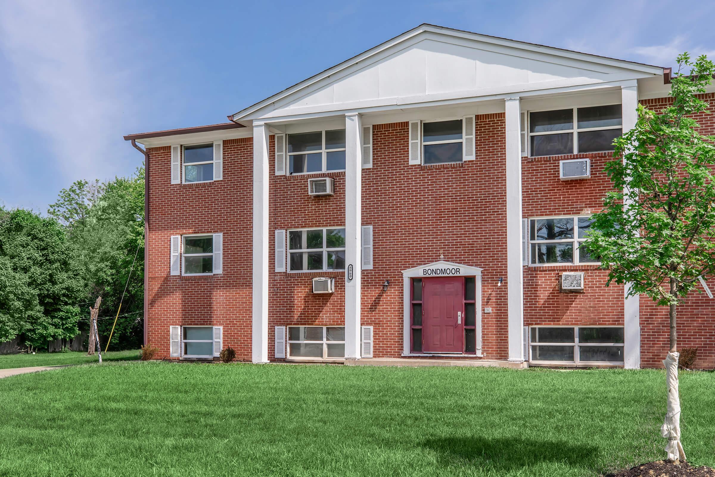 a large brick building with grass in front of a house