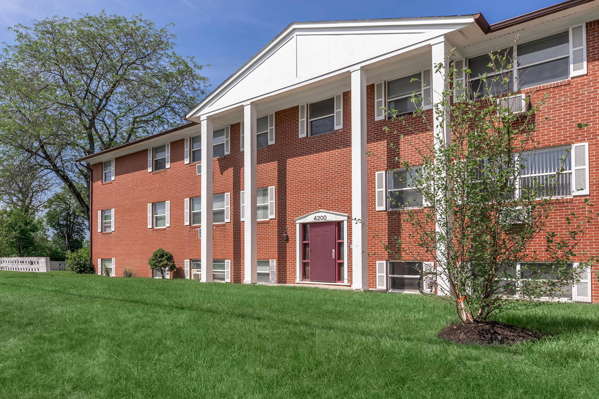 a large brick building with grass in front of a house