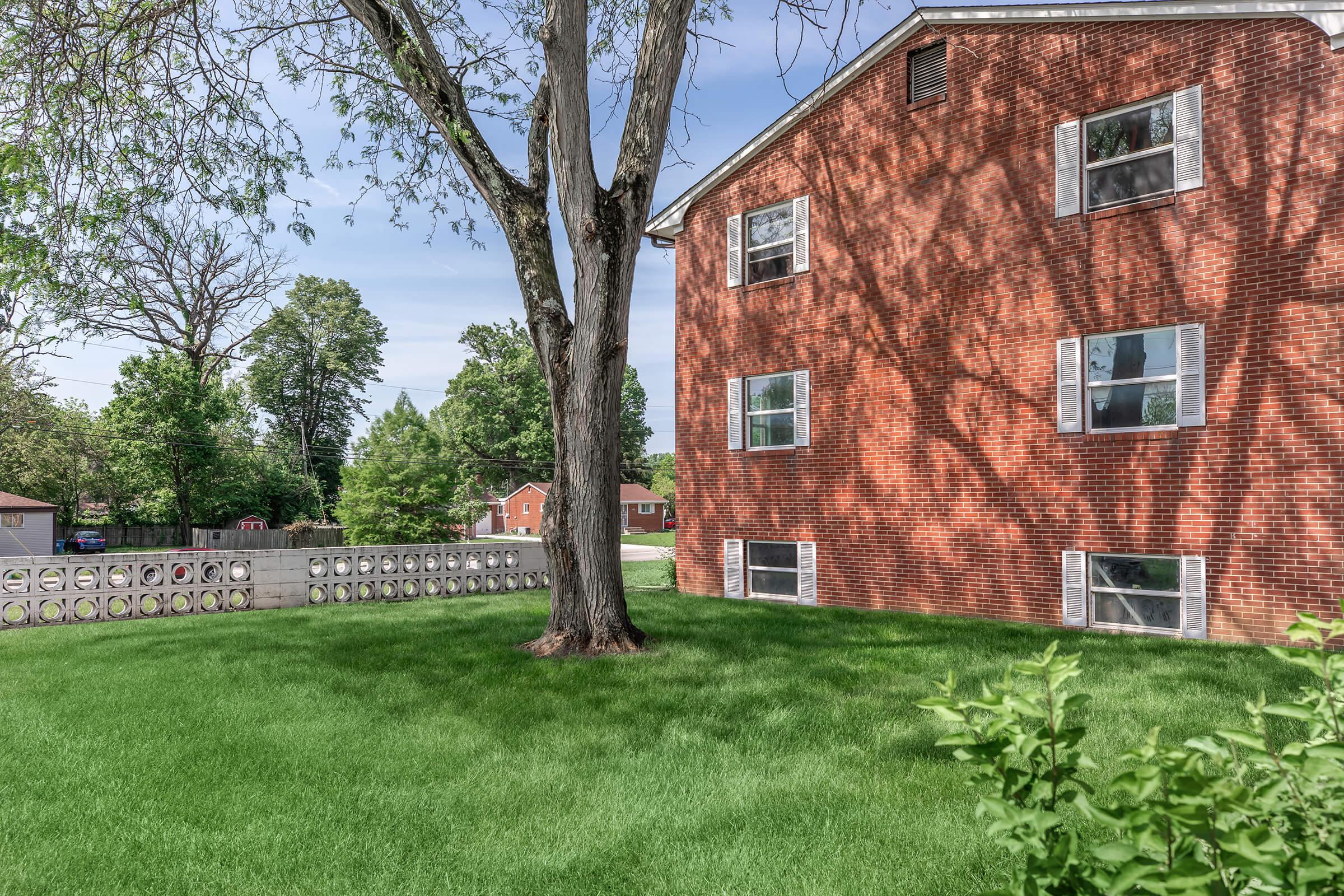 a large brick building with green grass in front of a house