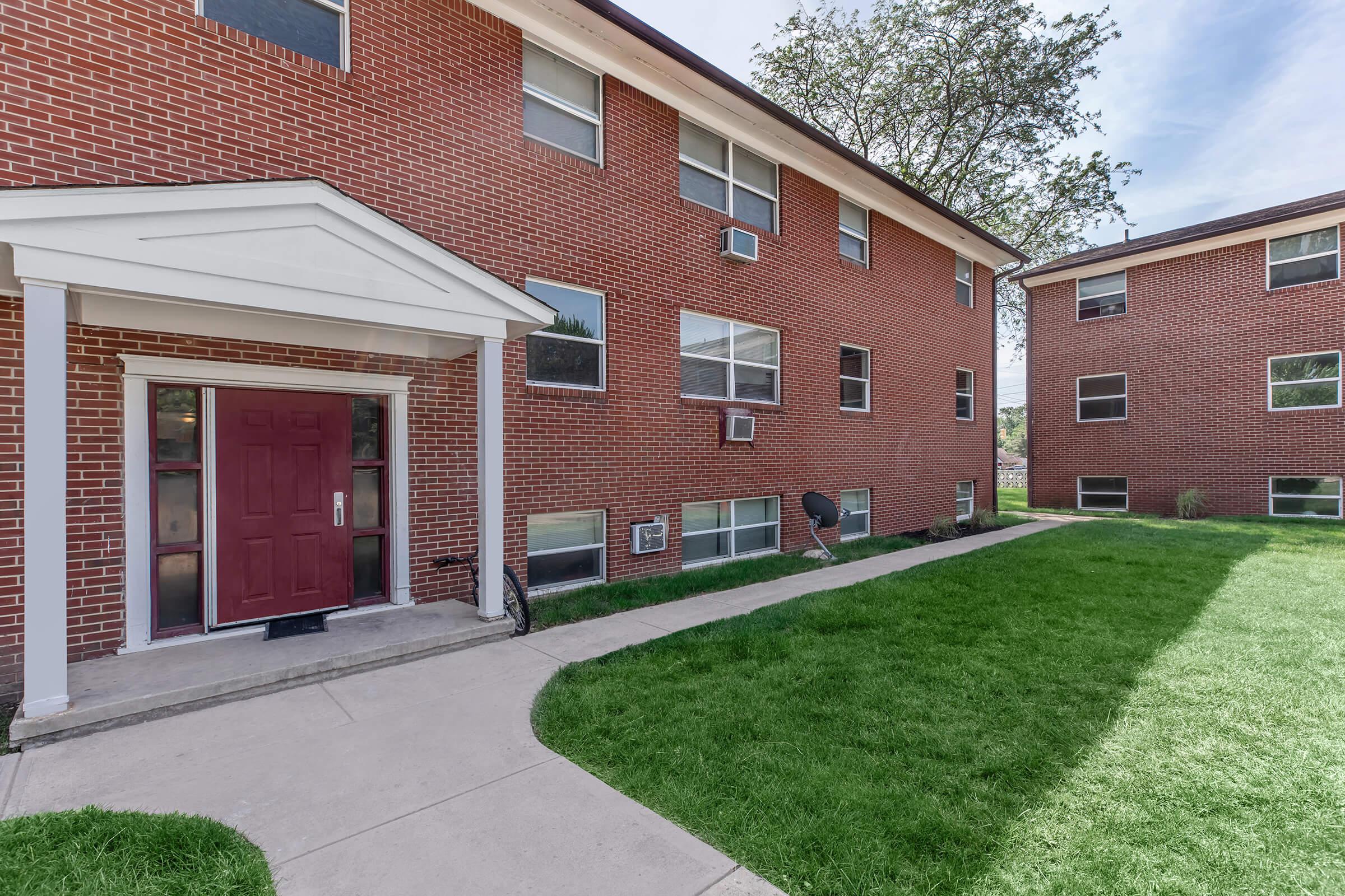 a house with a lawn in front of a brick building