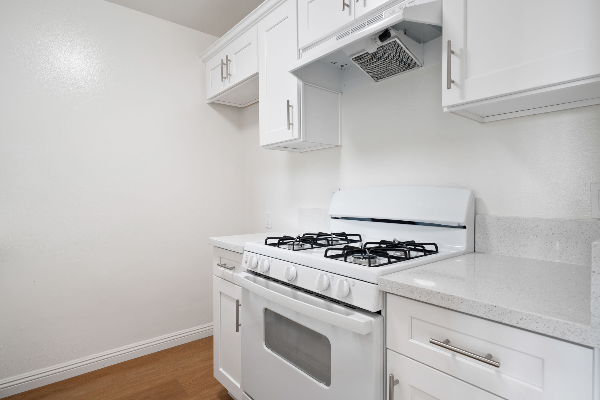 Modern kitchen featuring a white gas stove and oven, with white cabinets and a sleek countertop. The walls are a light color, enhancing the bright and clean atmosphere of the space. The kitchen is well-organized with ample cabinetry for storage.