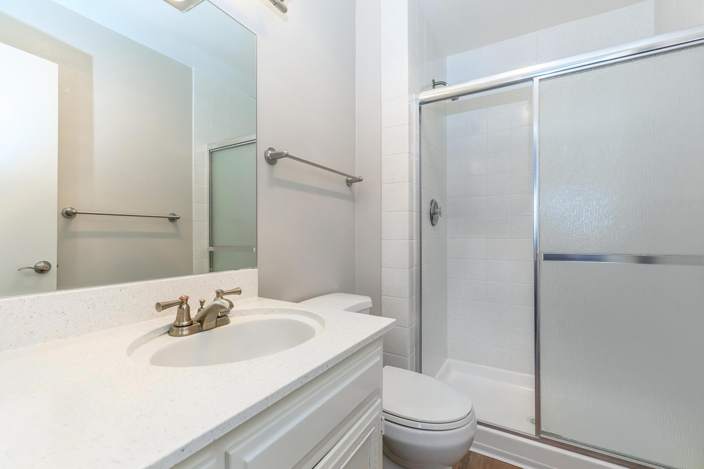 a white sink sitting under a mirror