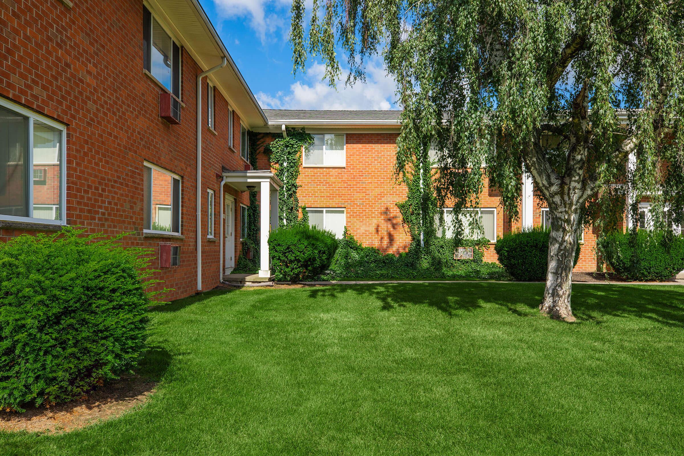 a large brick building with grass in front of a house