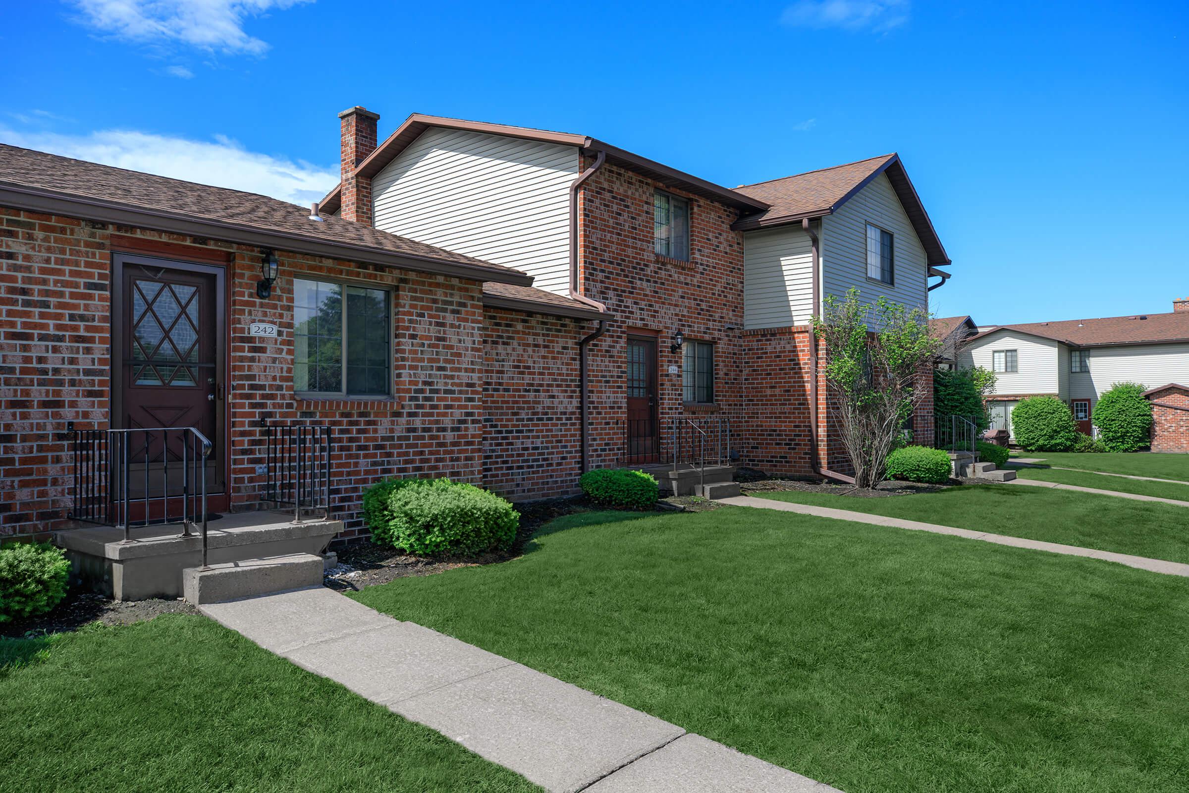 a large brick building with grass in front of a house