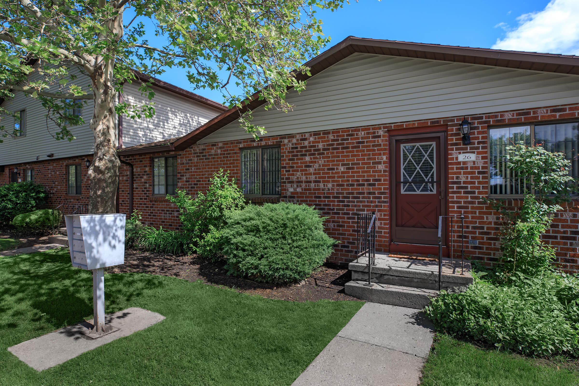 a house with bushes in front of a brick building