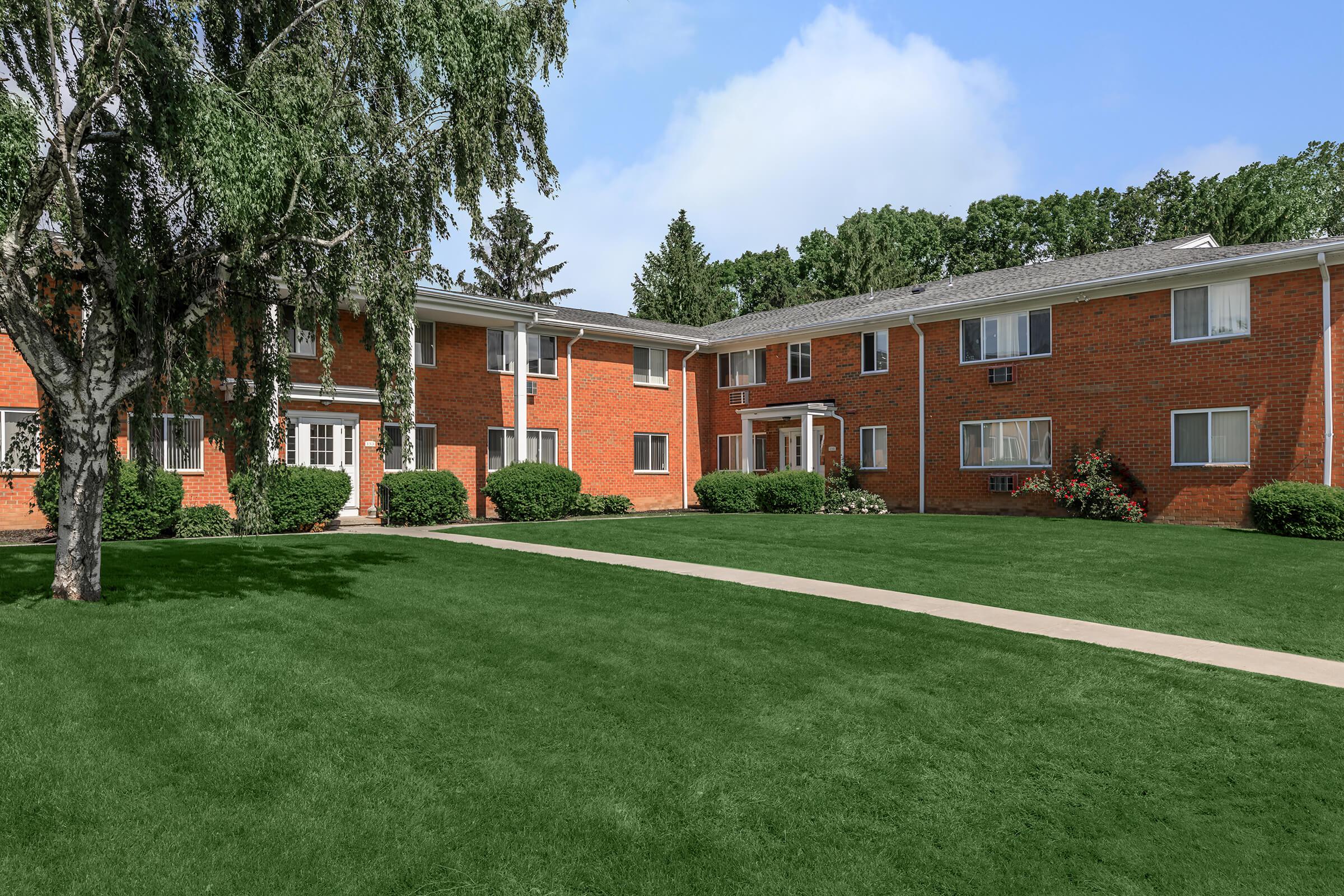 a large brick building with green grass in front of a house