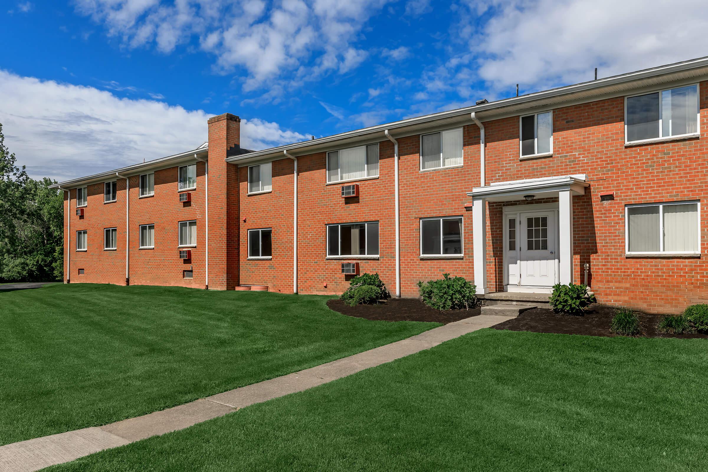 a large brick building with grass in front of a house