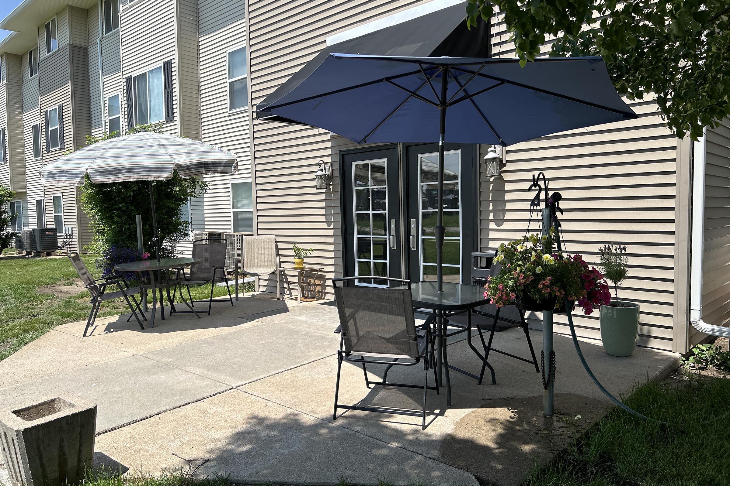 a lawn chair under an umbrella in front of a house