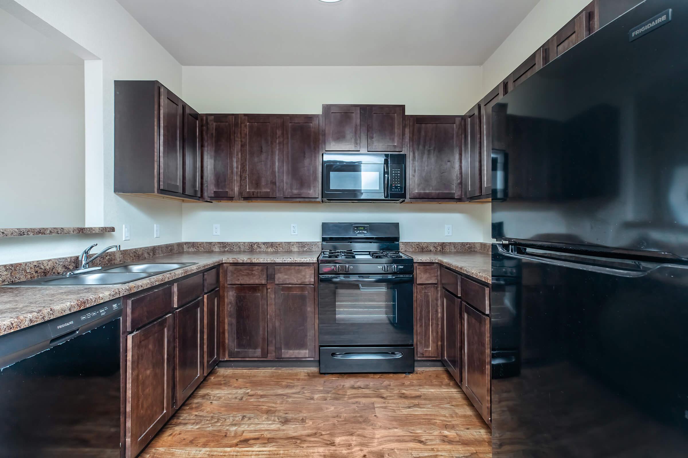 a large kitchen with stainless steel appliances and wooden cabinets