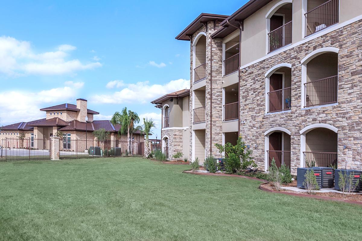 a large brick building with grass in front of a house