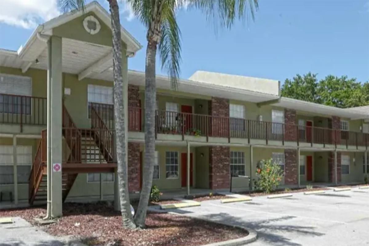 a house with trees in front of a brick building