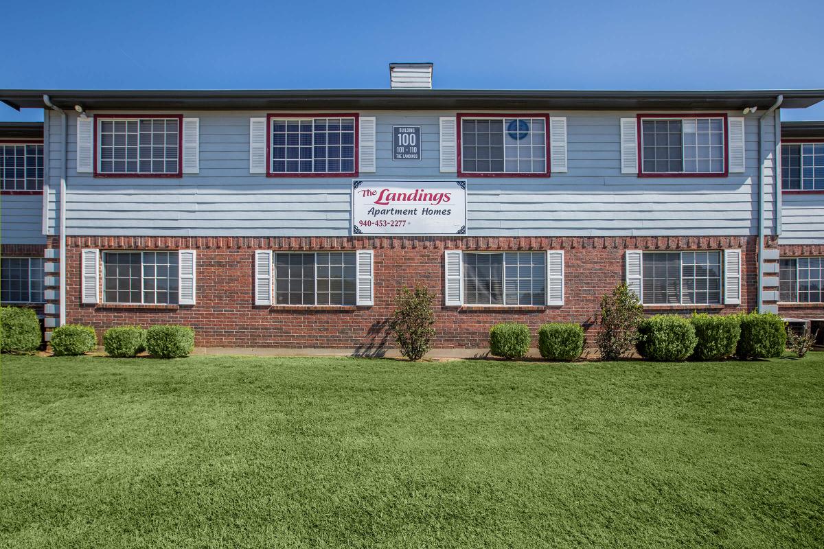 a large brick building with grass in front of a house