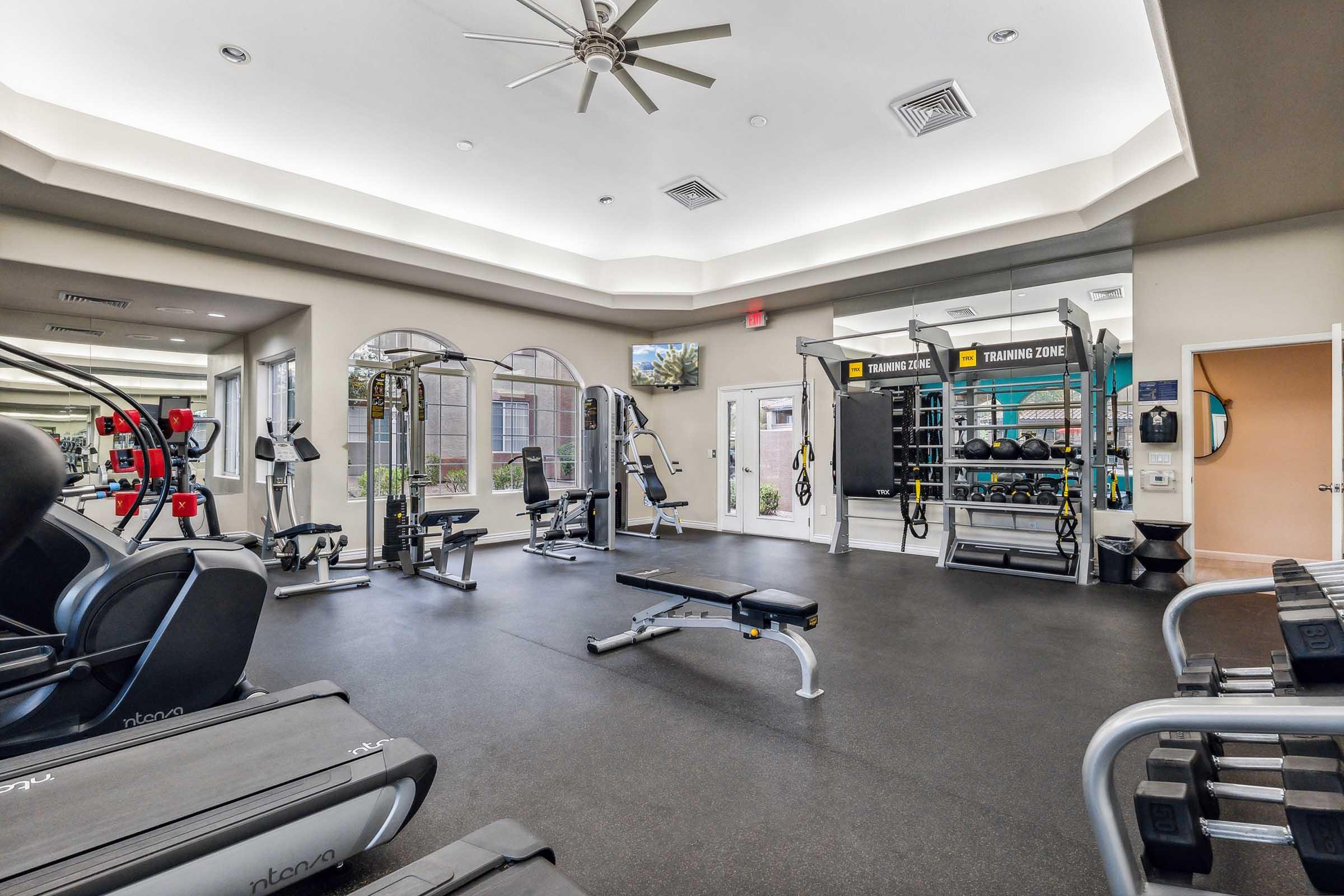 A modern gym interior featuring various workout equipment, including weight machines, free weights, and benches.