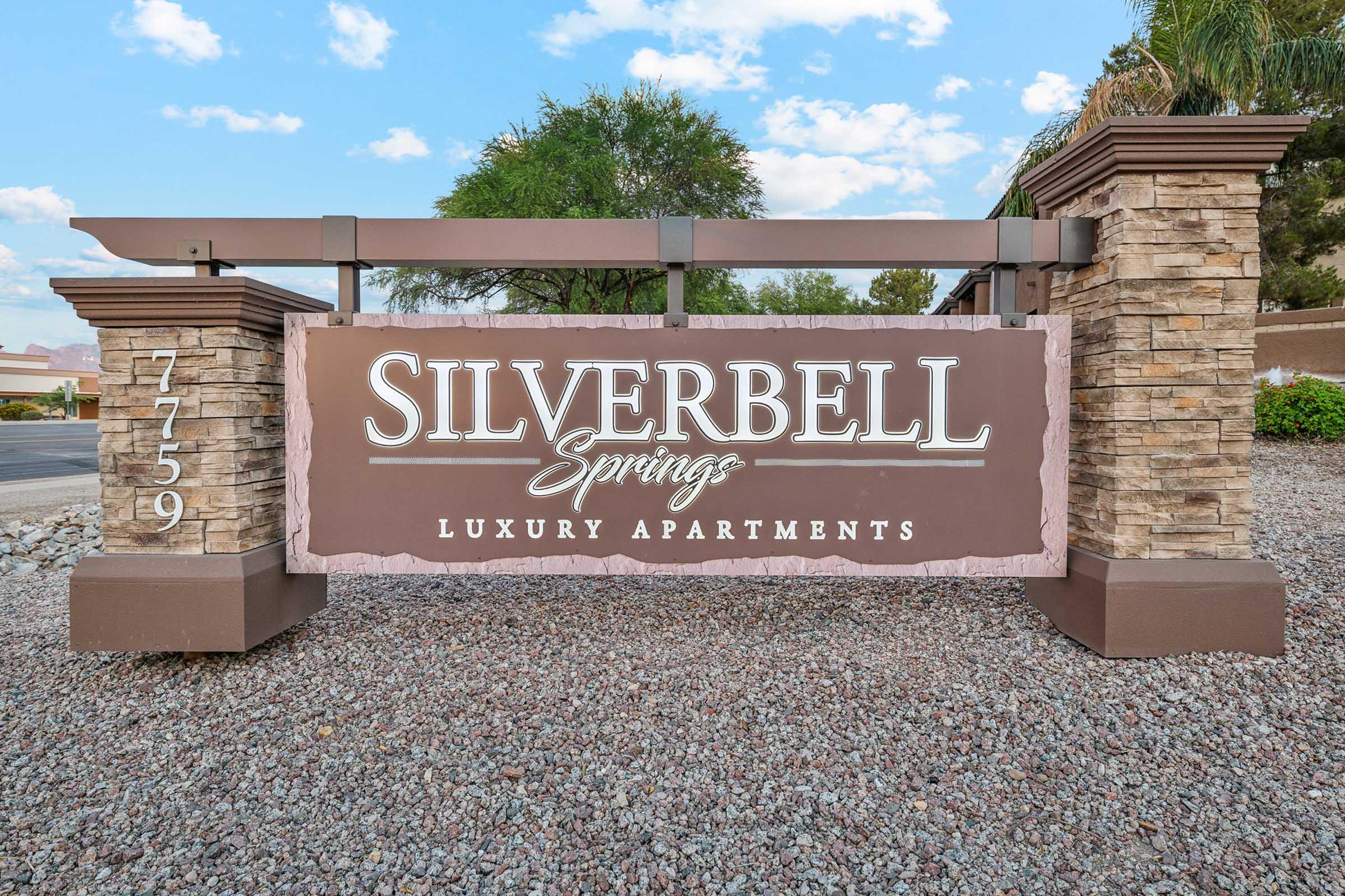 Sign for Silverbell Springs Luxury Apartments, featuring a large decorative name prominently displayed against a background of stone