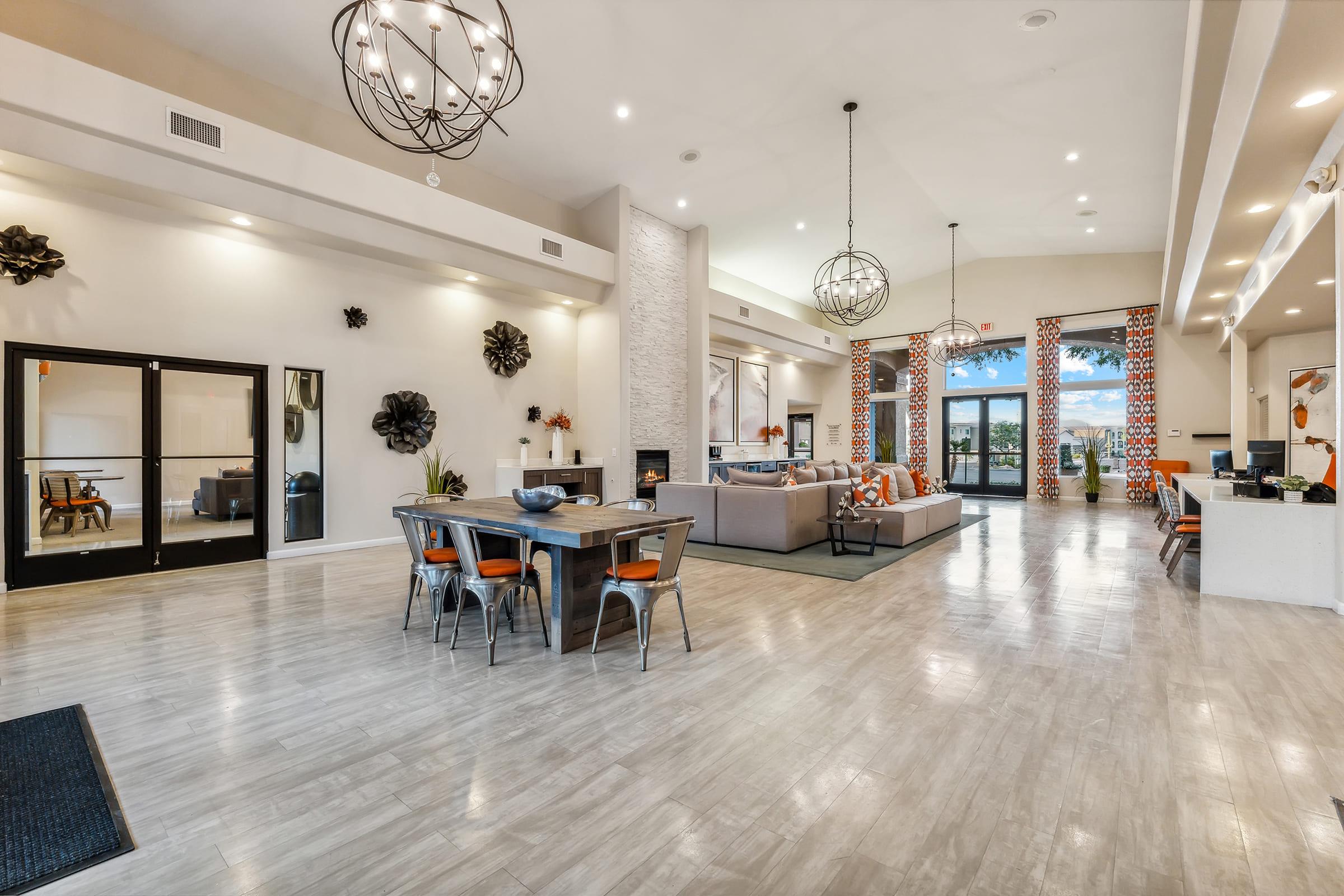 A spacious, modern living area featuring a dining table with metal chairs, a cozy seating arrangement, large windows with patterned curtains, and an inviting fireplace.