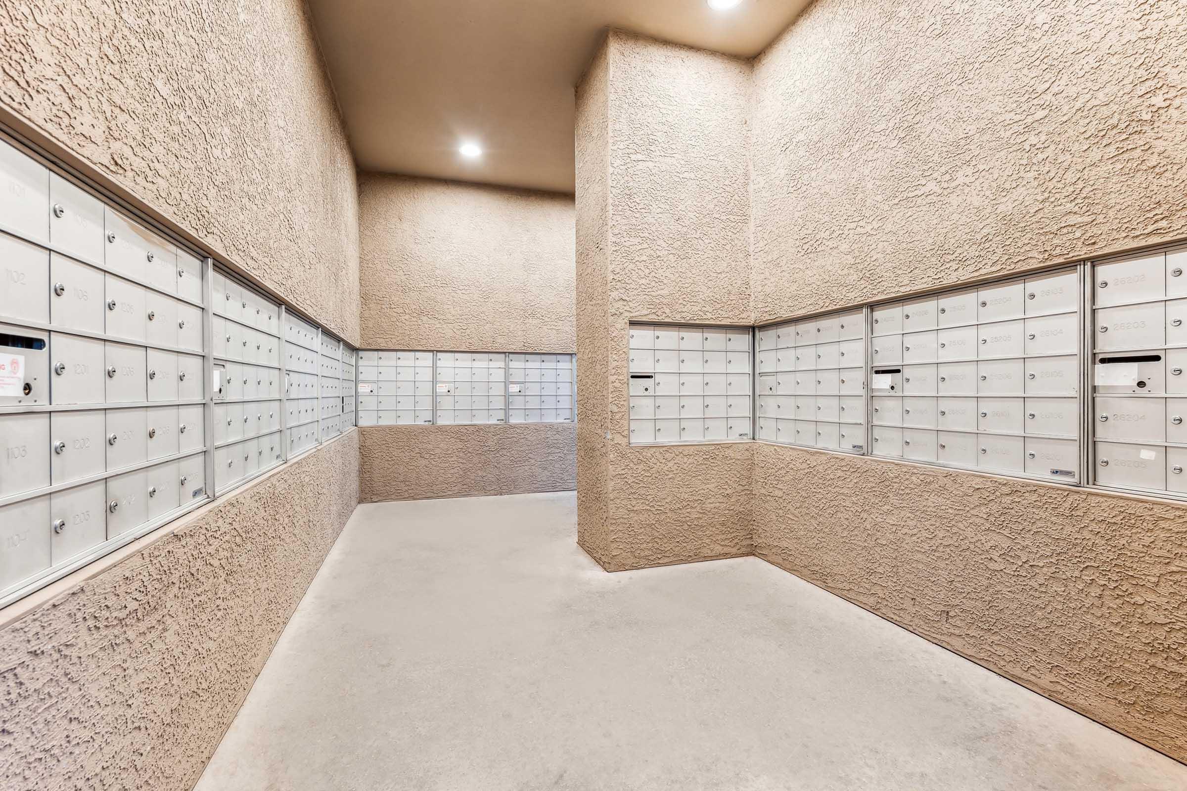 Interior of a mailroom featuring multiple rows of secure mailboxes mounted on the walls.