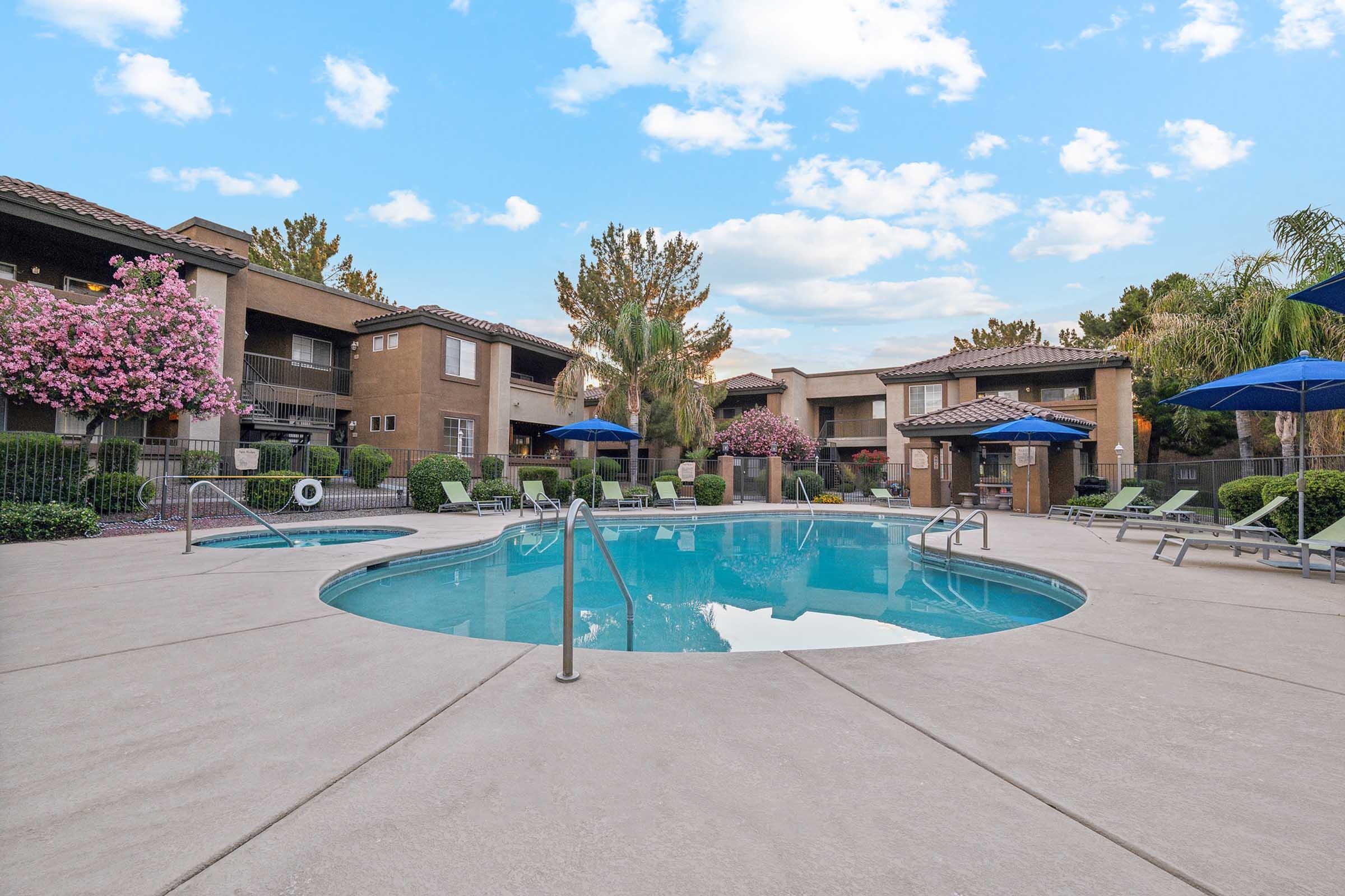 A clean and inviting outdoor swimming pool surrounded by lush greenery and blooming flowers.