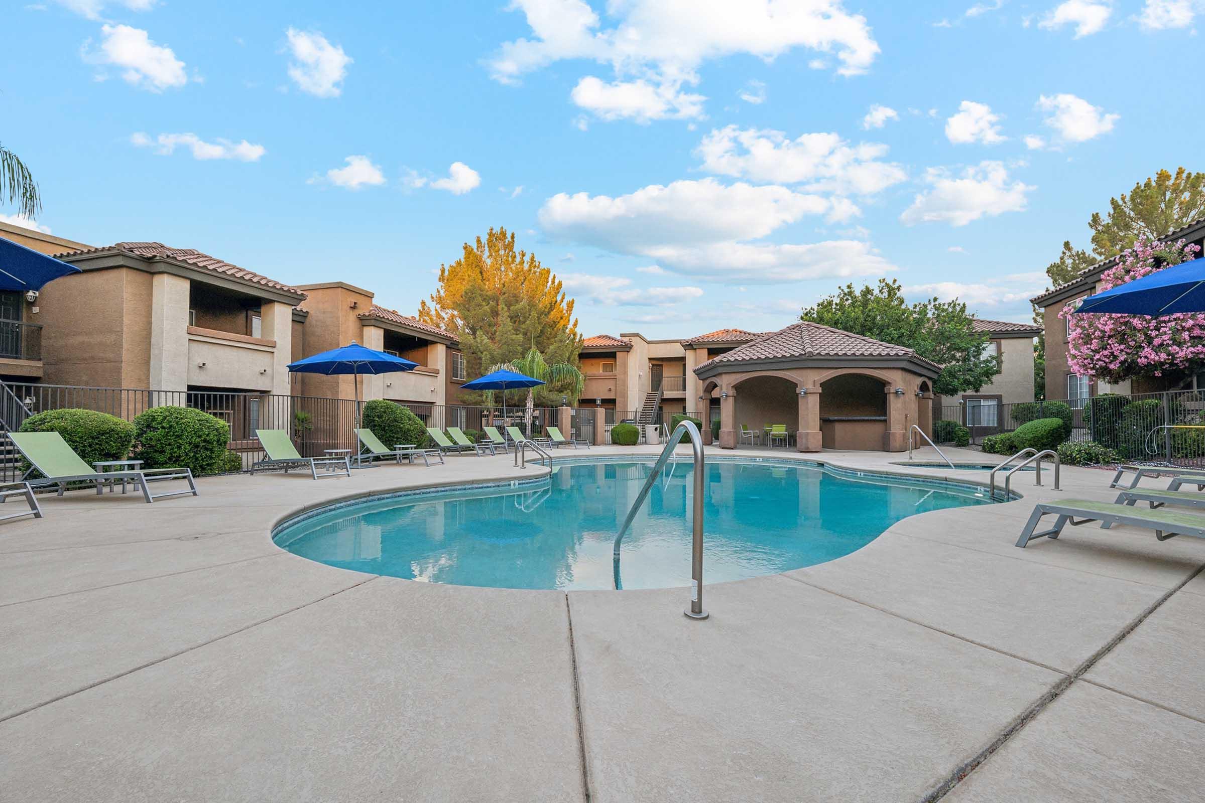 A tranquil outdoor swimming pool surrounded by lounge chairs and vibrant greenery.