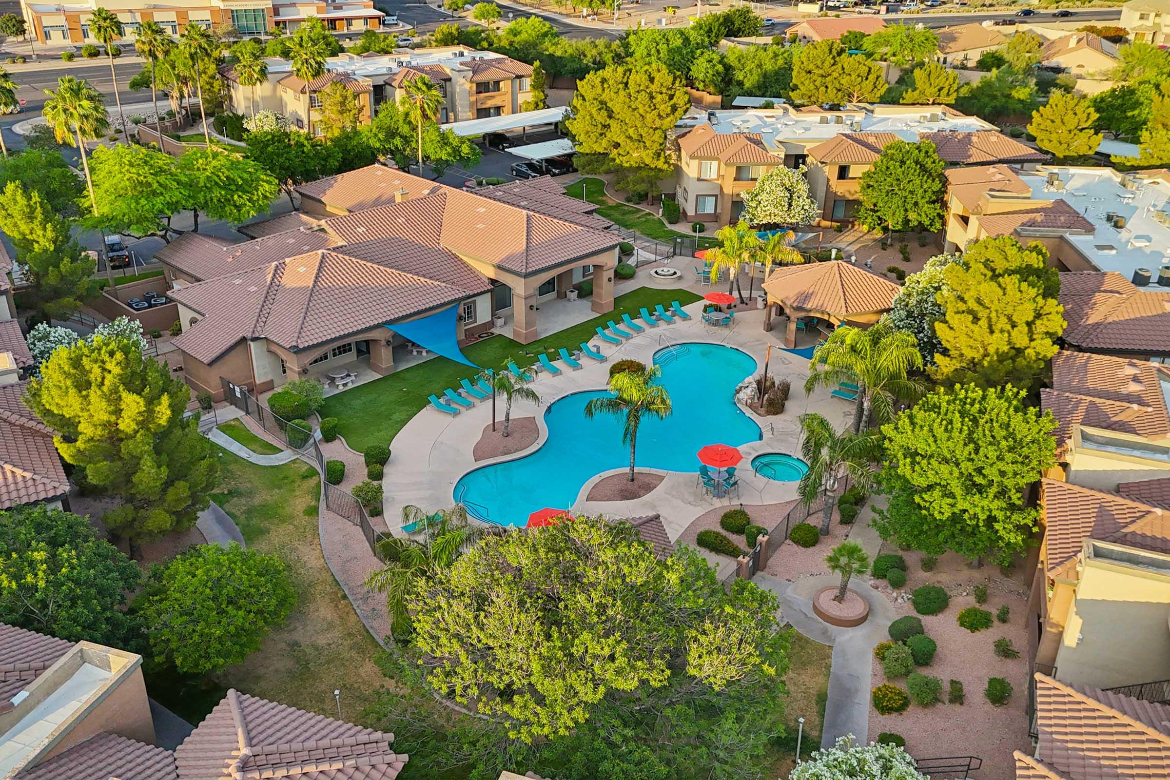 Aerial view of a residential community featuring a pool surrounded by palm trees and lounge chairs.