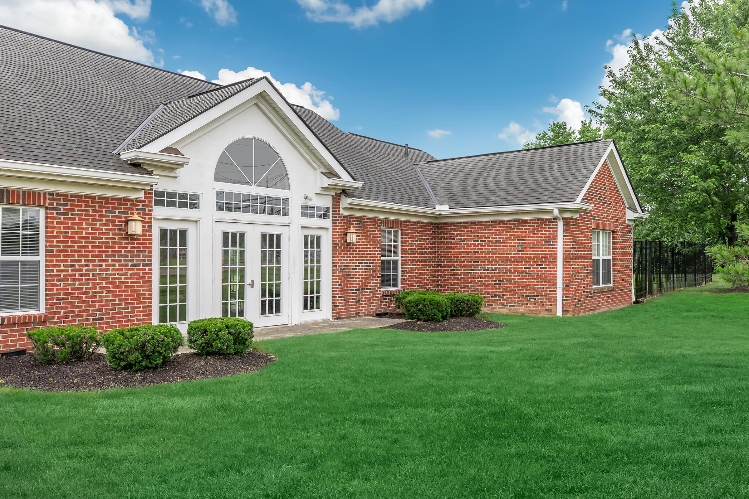 a large brick building with green grass in front of a house