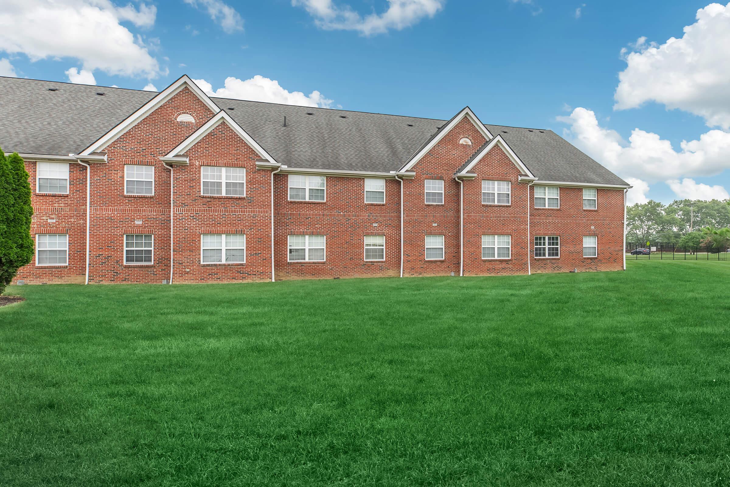 a large brick building with a grassy field