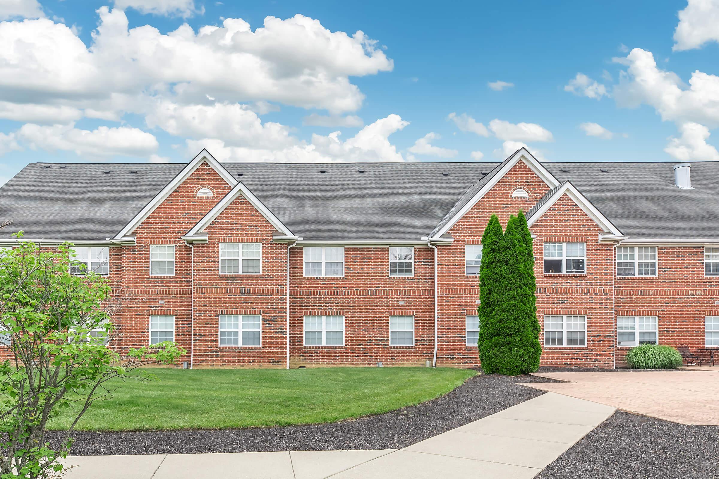 a large brick building with grass in front of a house