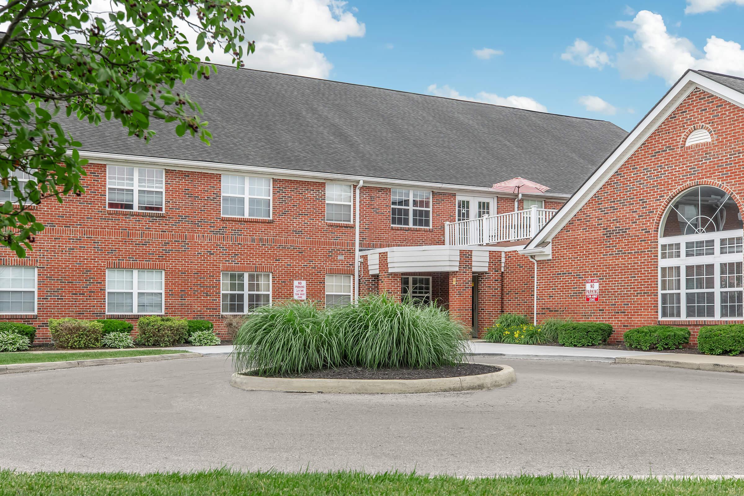 a large brick building with grass in front of a house