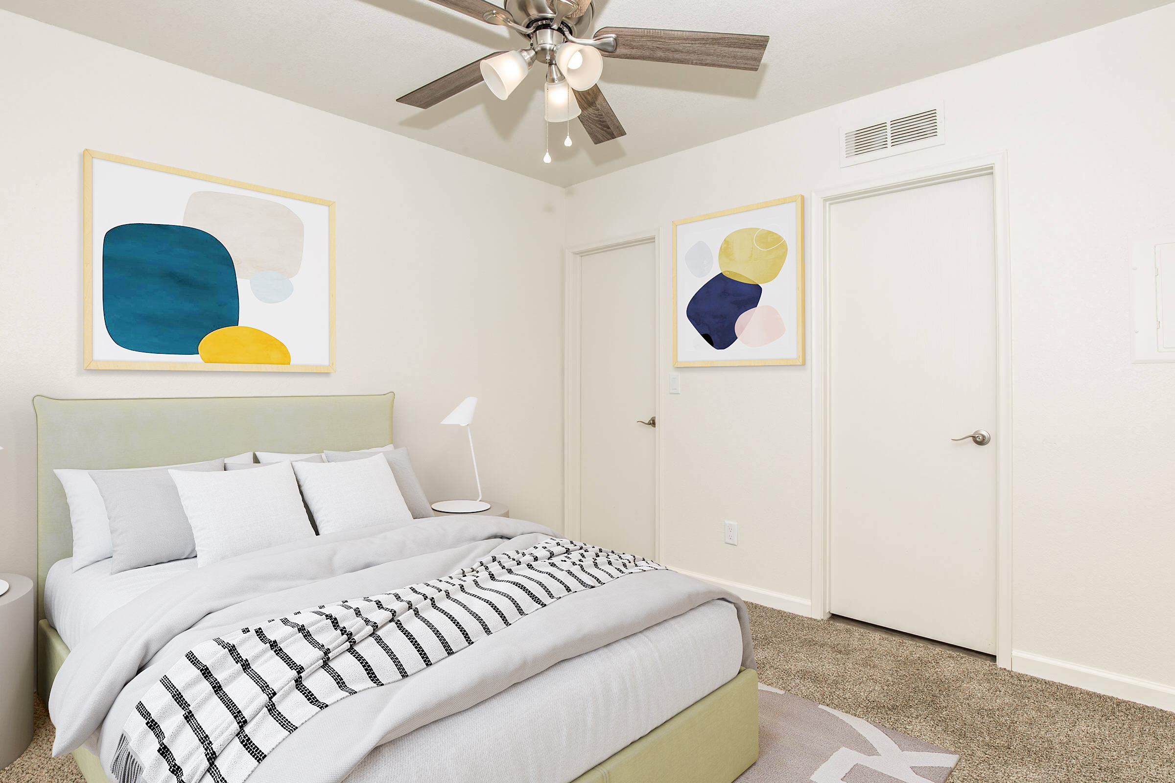 A modern bedroom featuring a light green bed with gray and white bedding. Two abstract art pieces are on the wall, and a ceiling fan with light fixtures is visible. There is a door on the right and a side table with a lamp beside the bed, all set in a neutral color scheme with carpeted flooring.