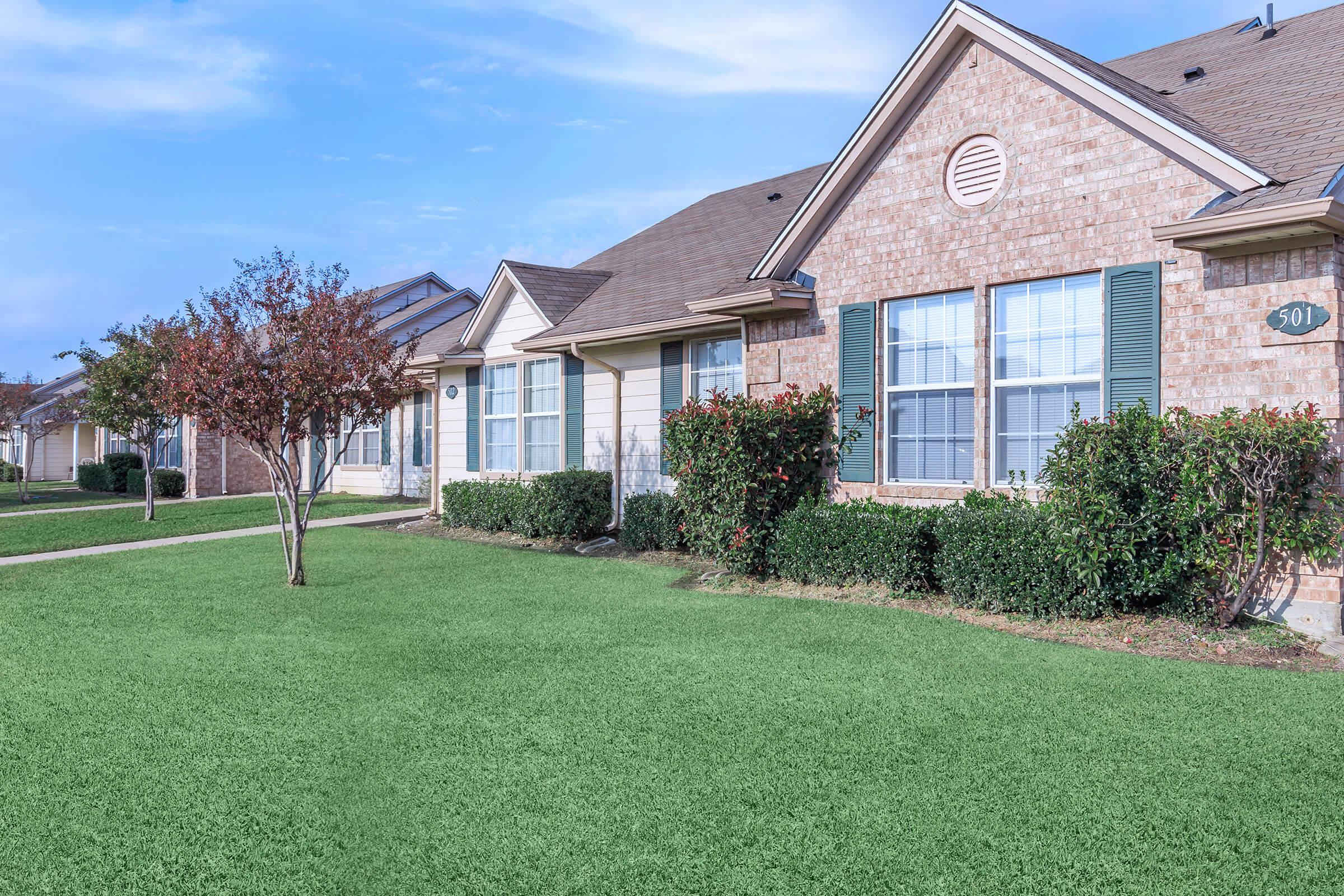 a large brick building with green grass in front of a house