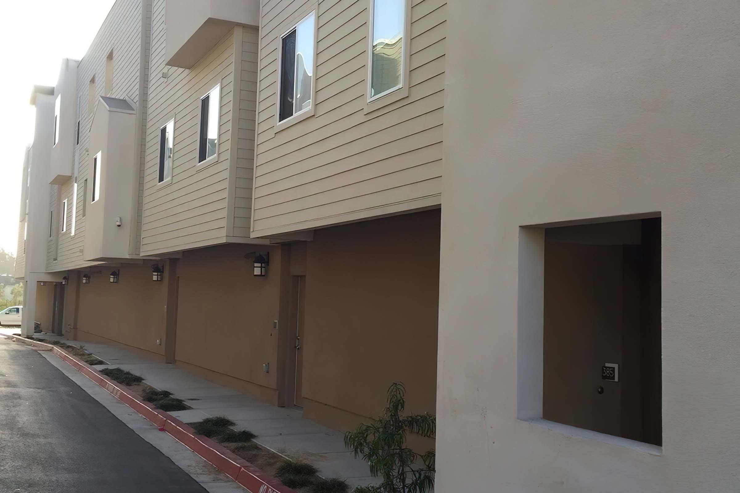 A view of a modern apartment complex featuring light-colored siding and several windows.