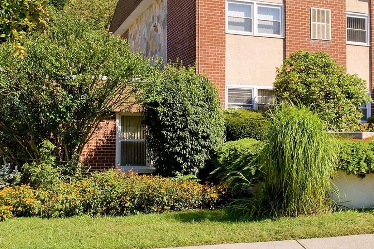 a house with bushes in front of a brick building