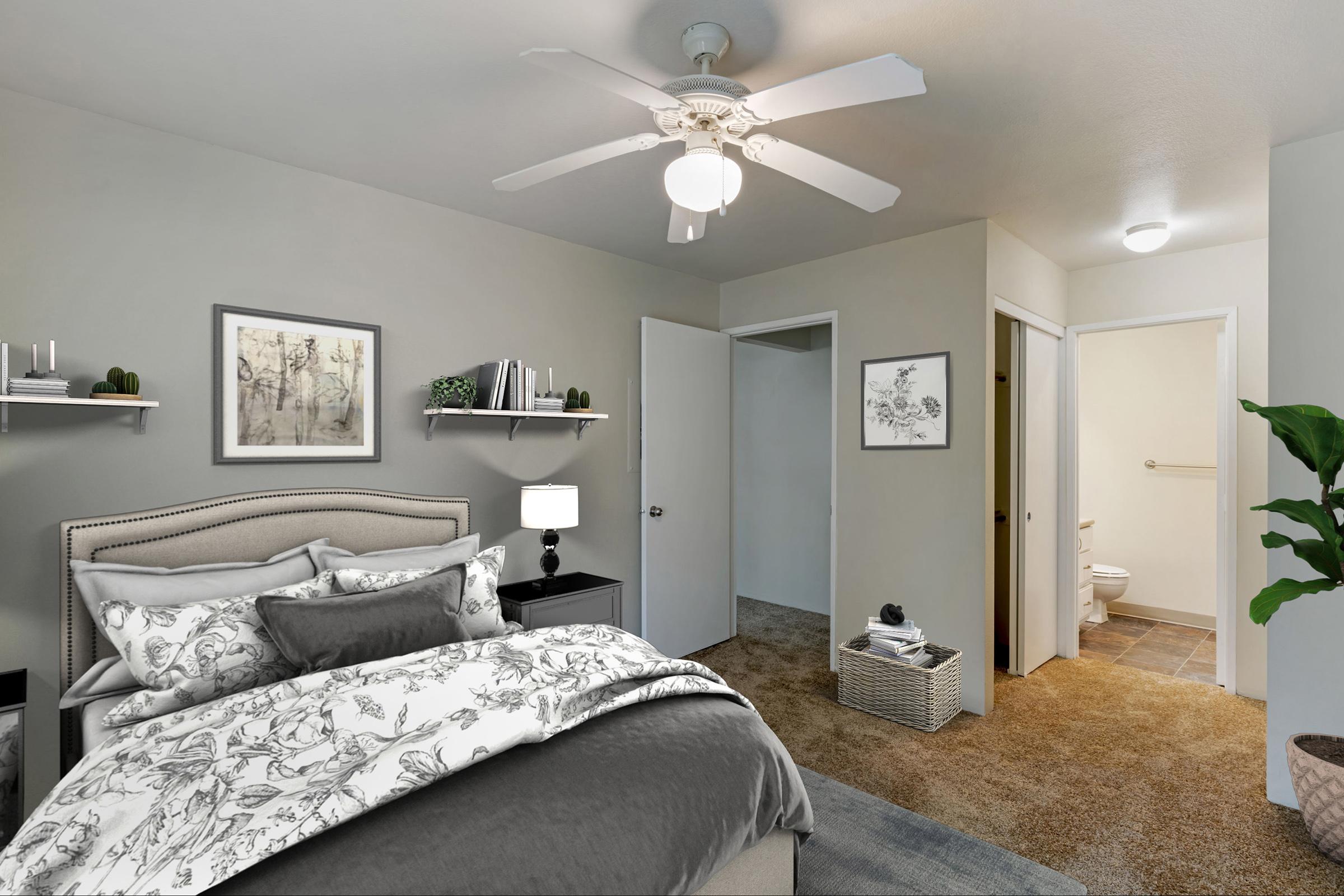 A cozy bedroom featuring a queen-sized bed with decorative bedding, a ceiling fan, and soft lighting.