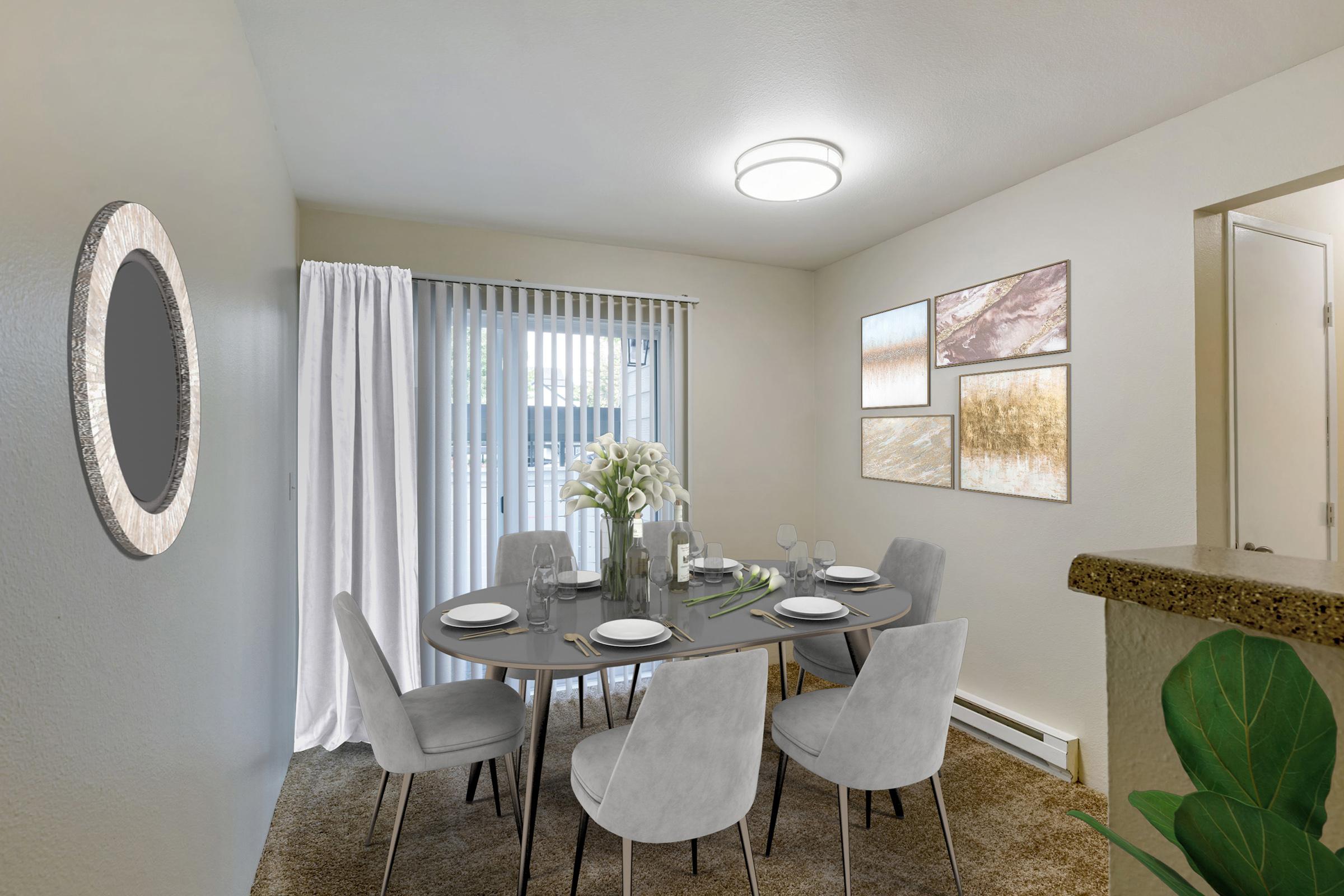 A modern dining room featuring a round table set for six with grey upholstered chairs.