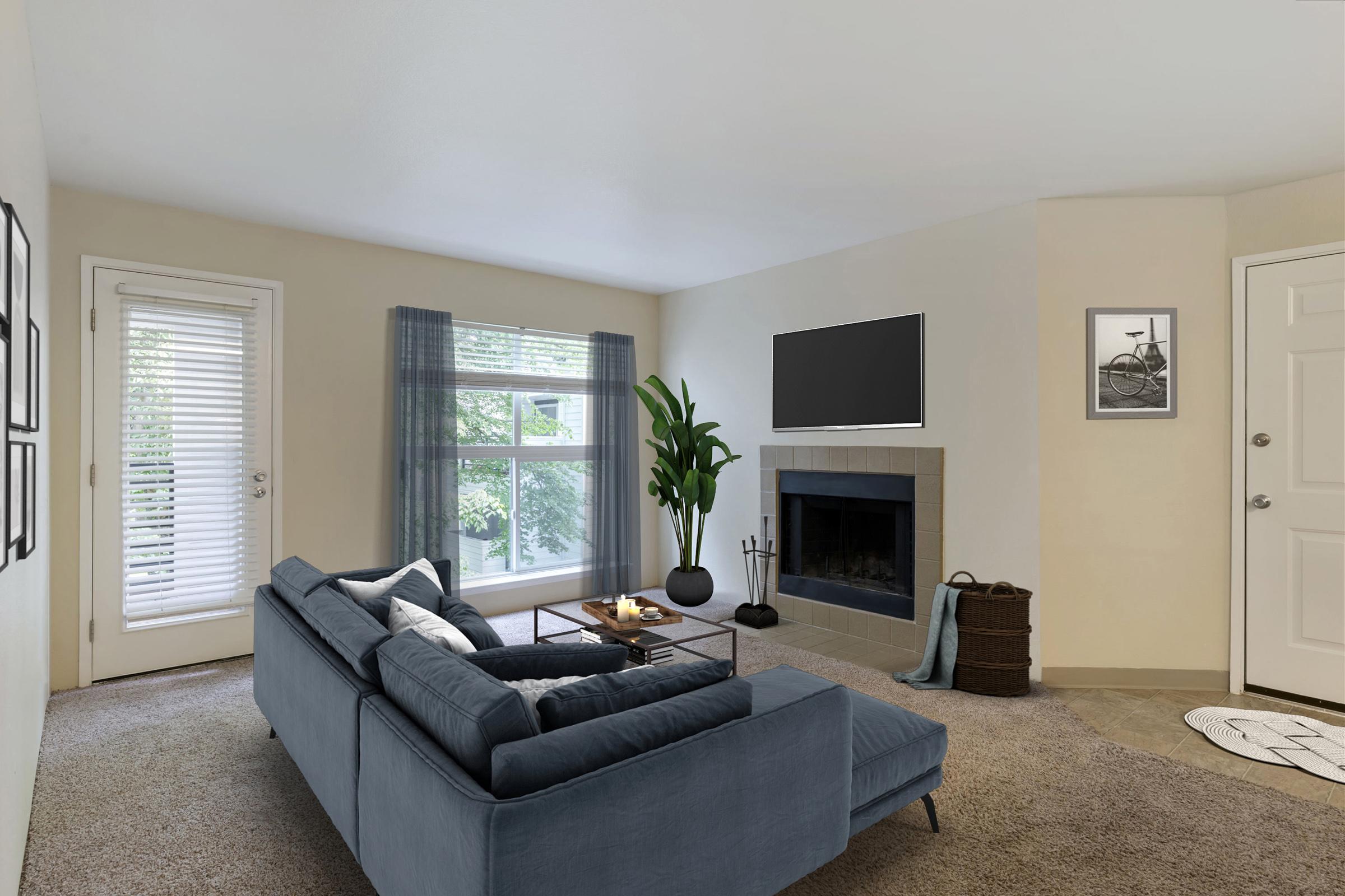 A cozy living room featuring a blue sectional sofa, a black coffee table, and a fireplace.