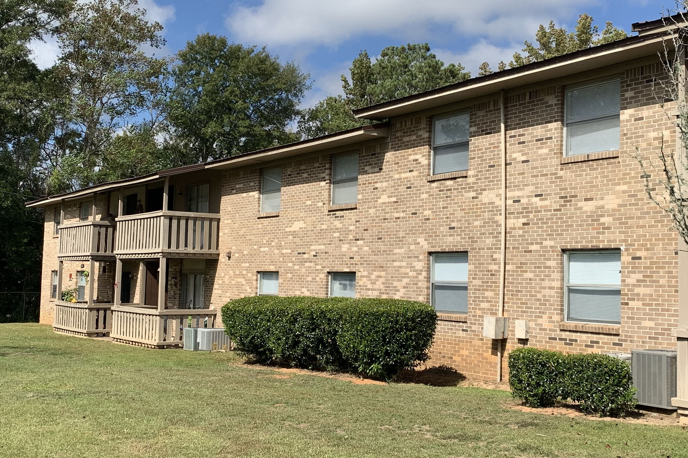 a large brick building with grass in front of a house