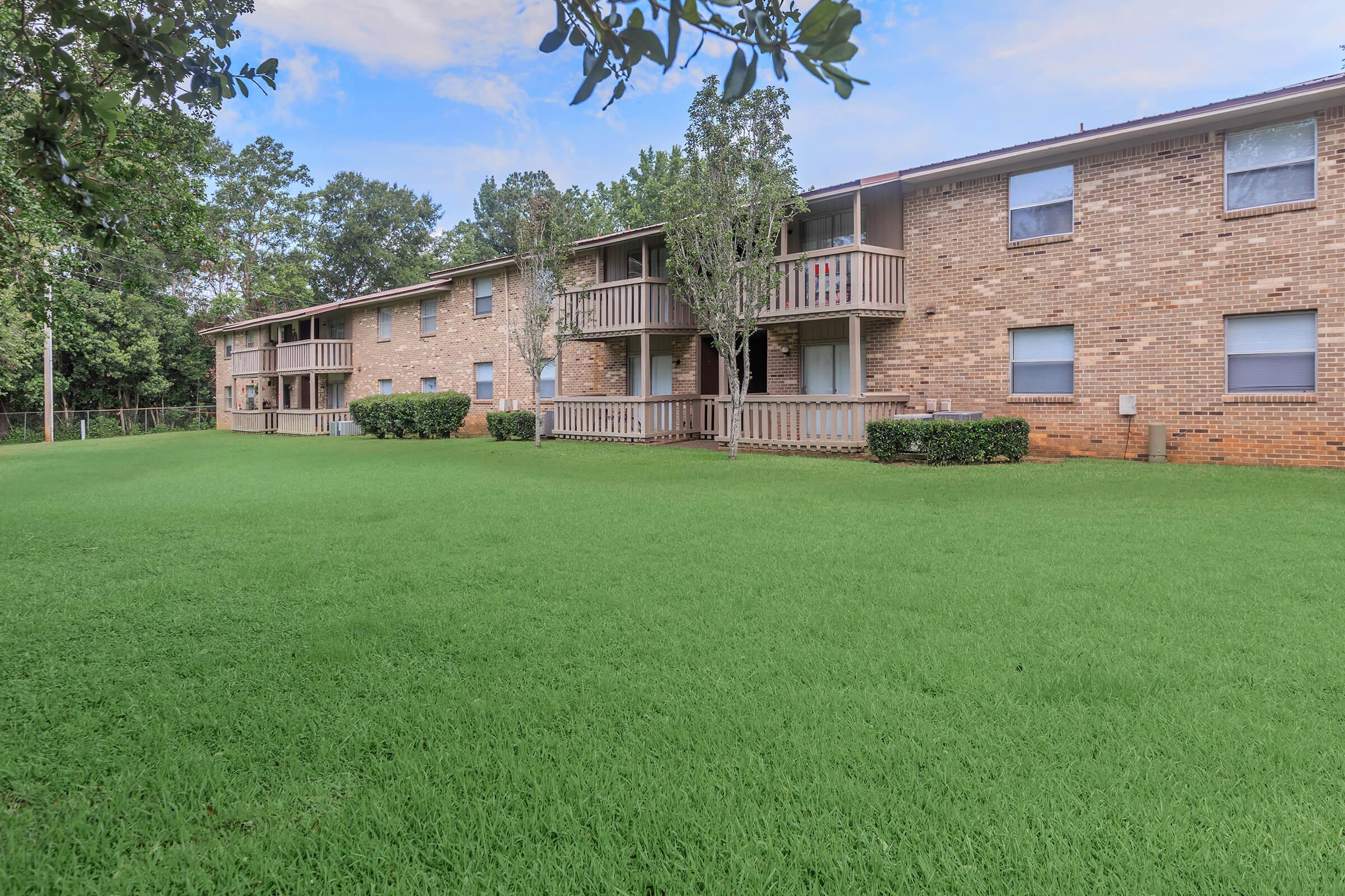 a large brick building with green grass in front of a house