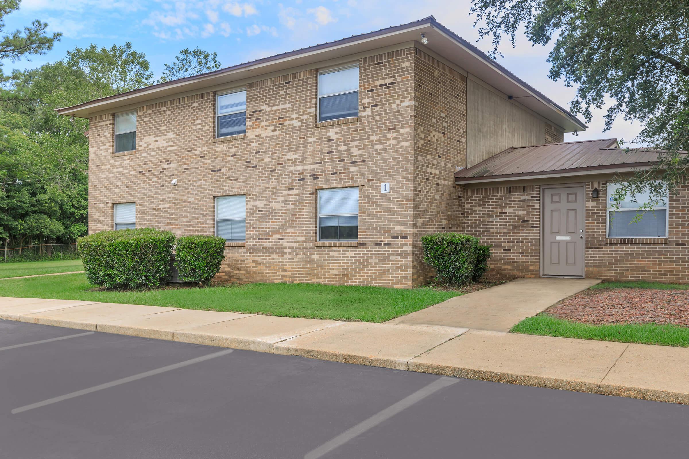 a large brick building with grass in front of a house