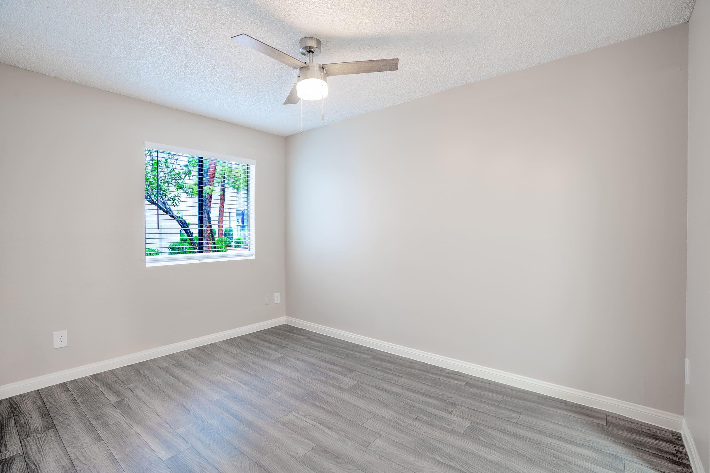 Open modern bedroom with ceiling fan and small window