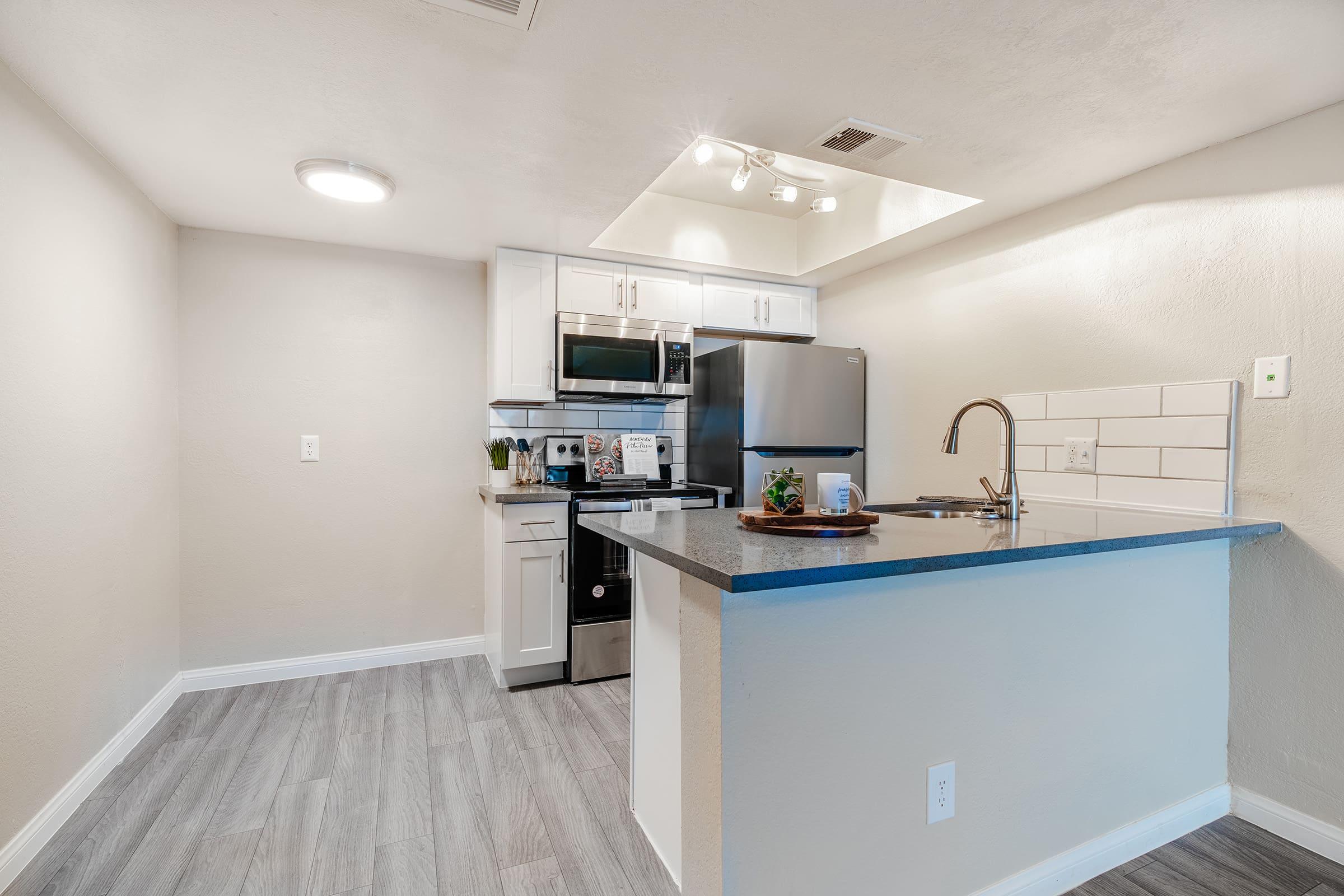 Fresh contemporary kitchen space with overhead lighting and large quartz island