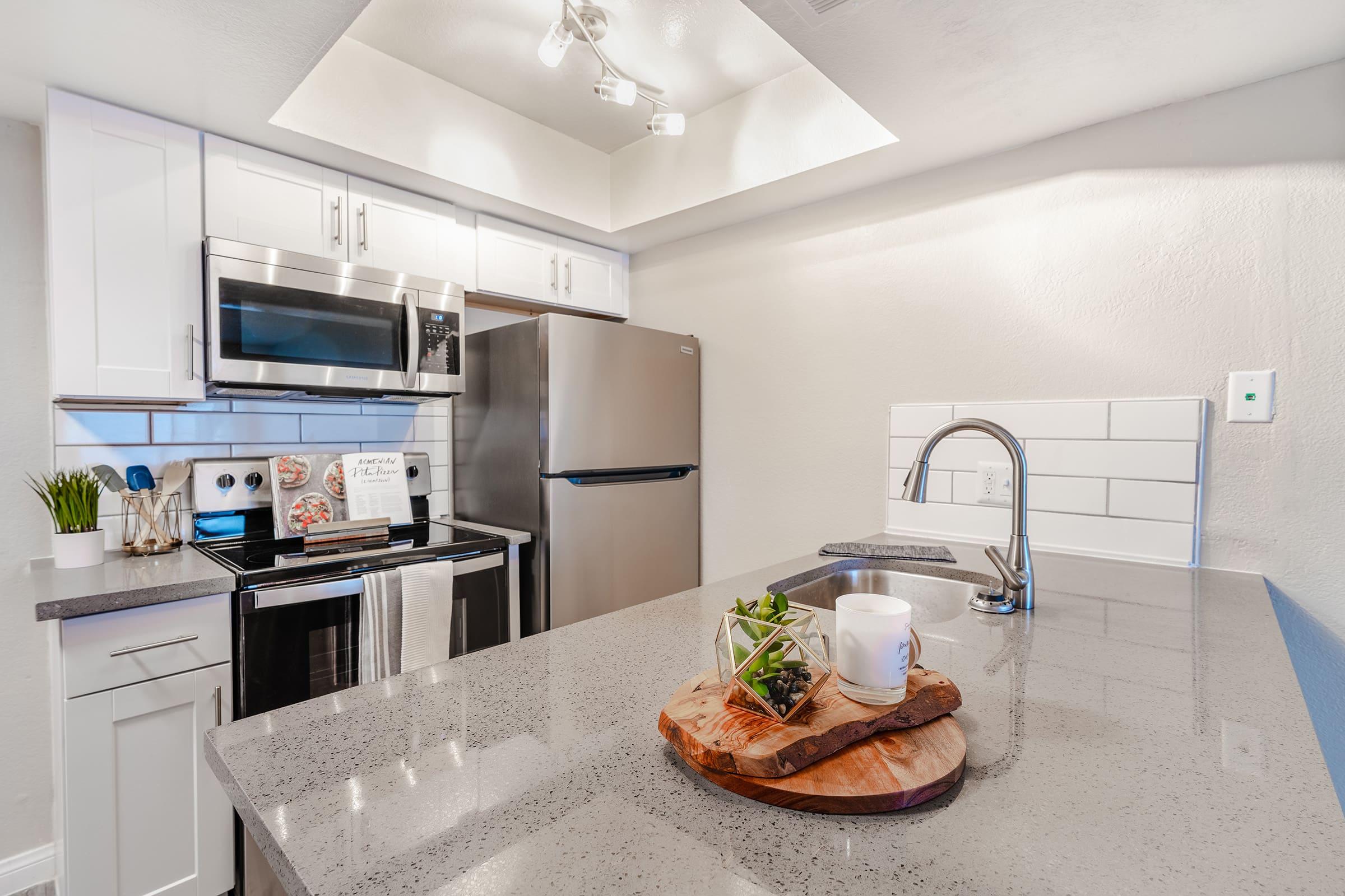 Fresh contemporary kitchen space with overhead lighting and large quartz island