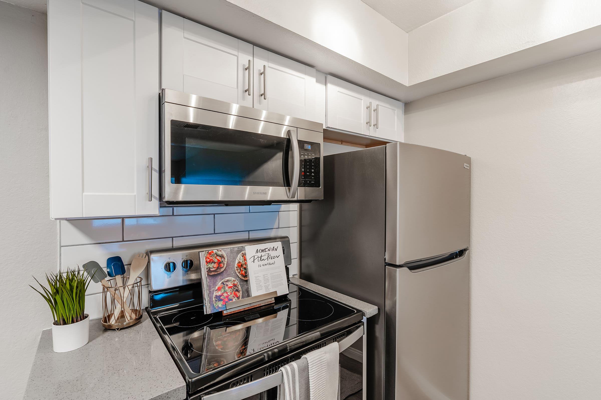 Close up of stainless steel appliances with a cookbook open on the stove top