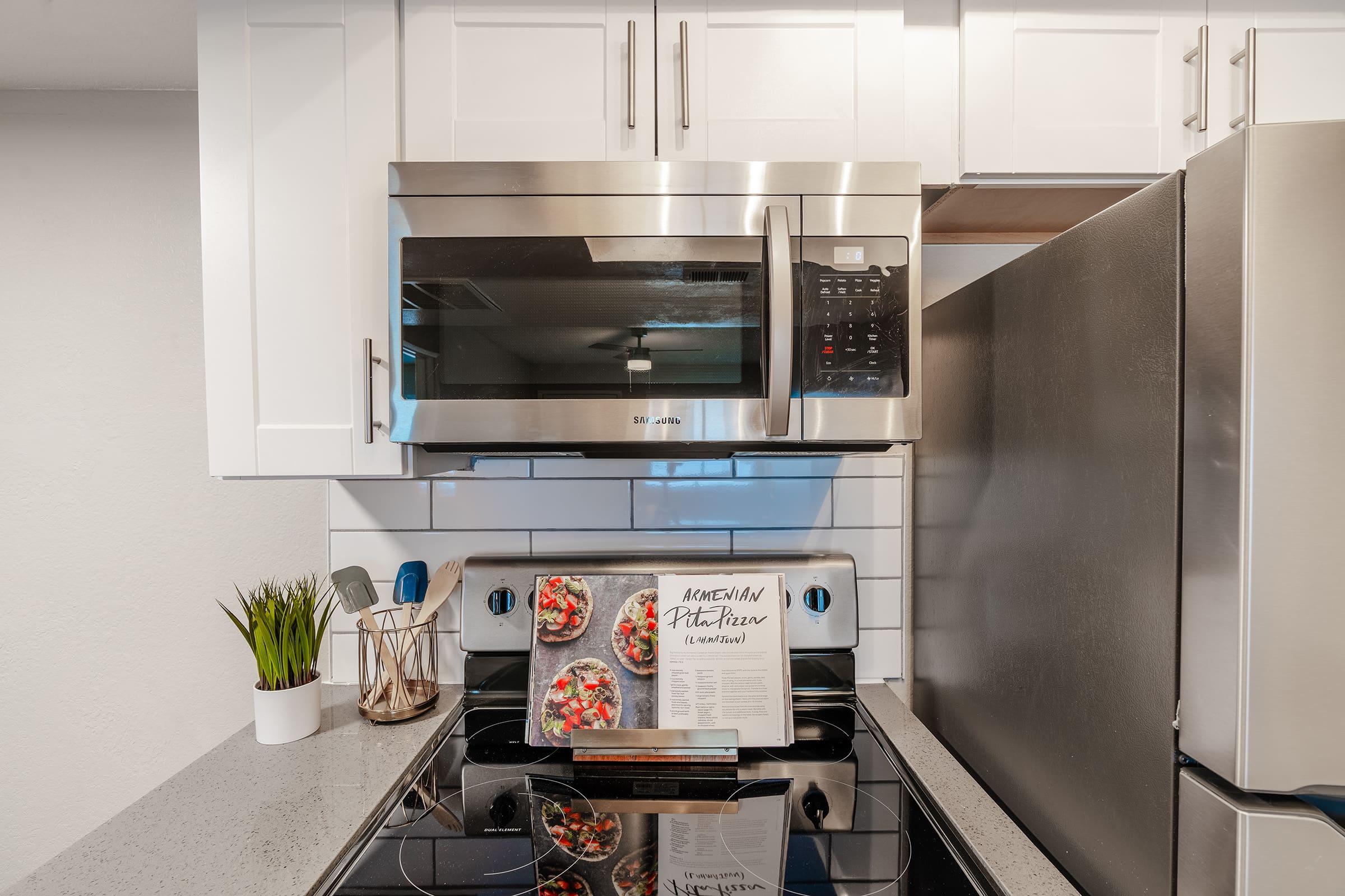 Close up of stainless steel appliances with a cookbook open on the stove top