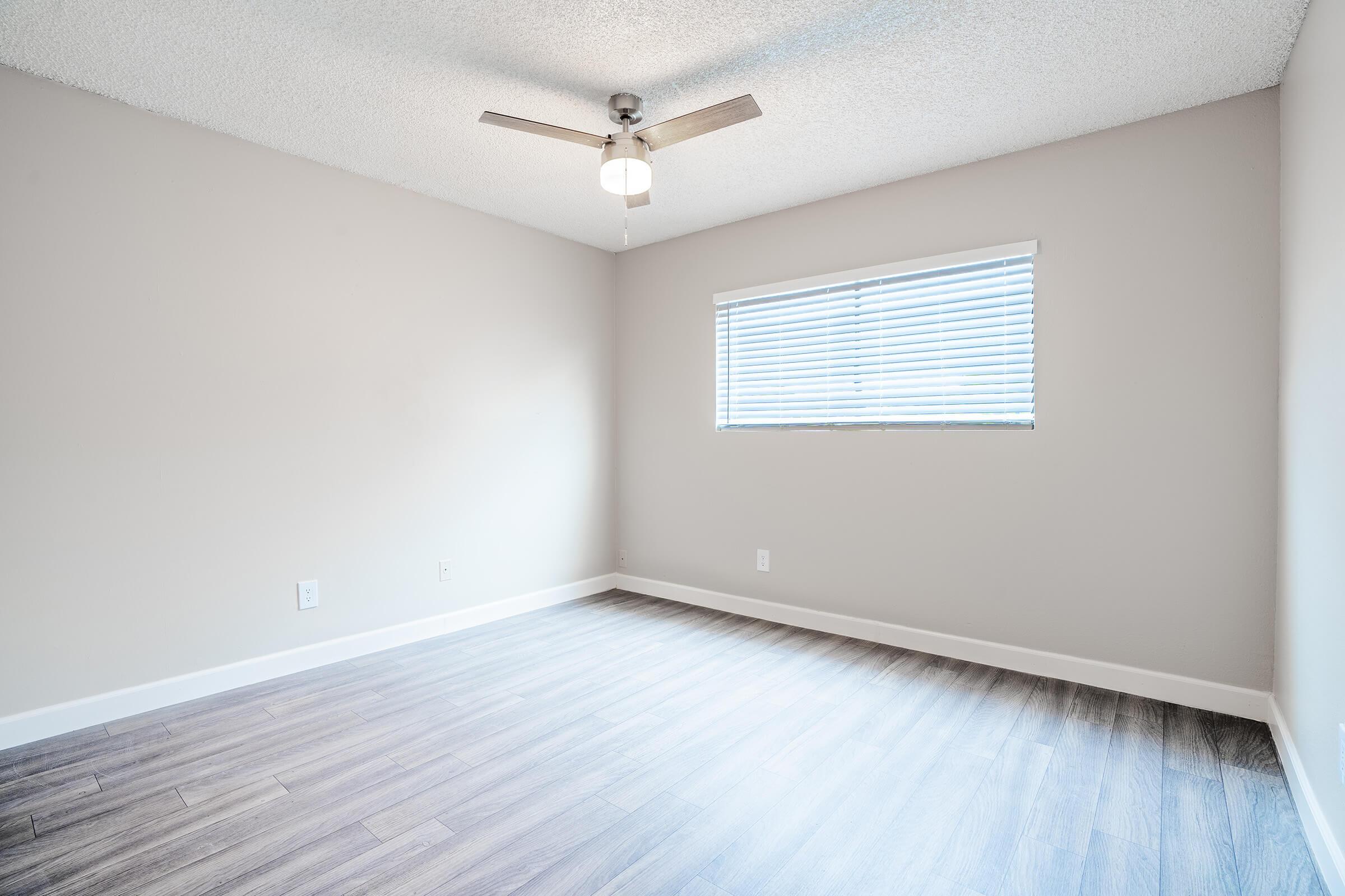 Large open bedroom with ceiling fan and small window