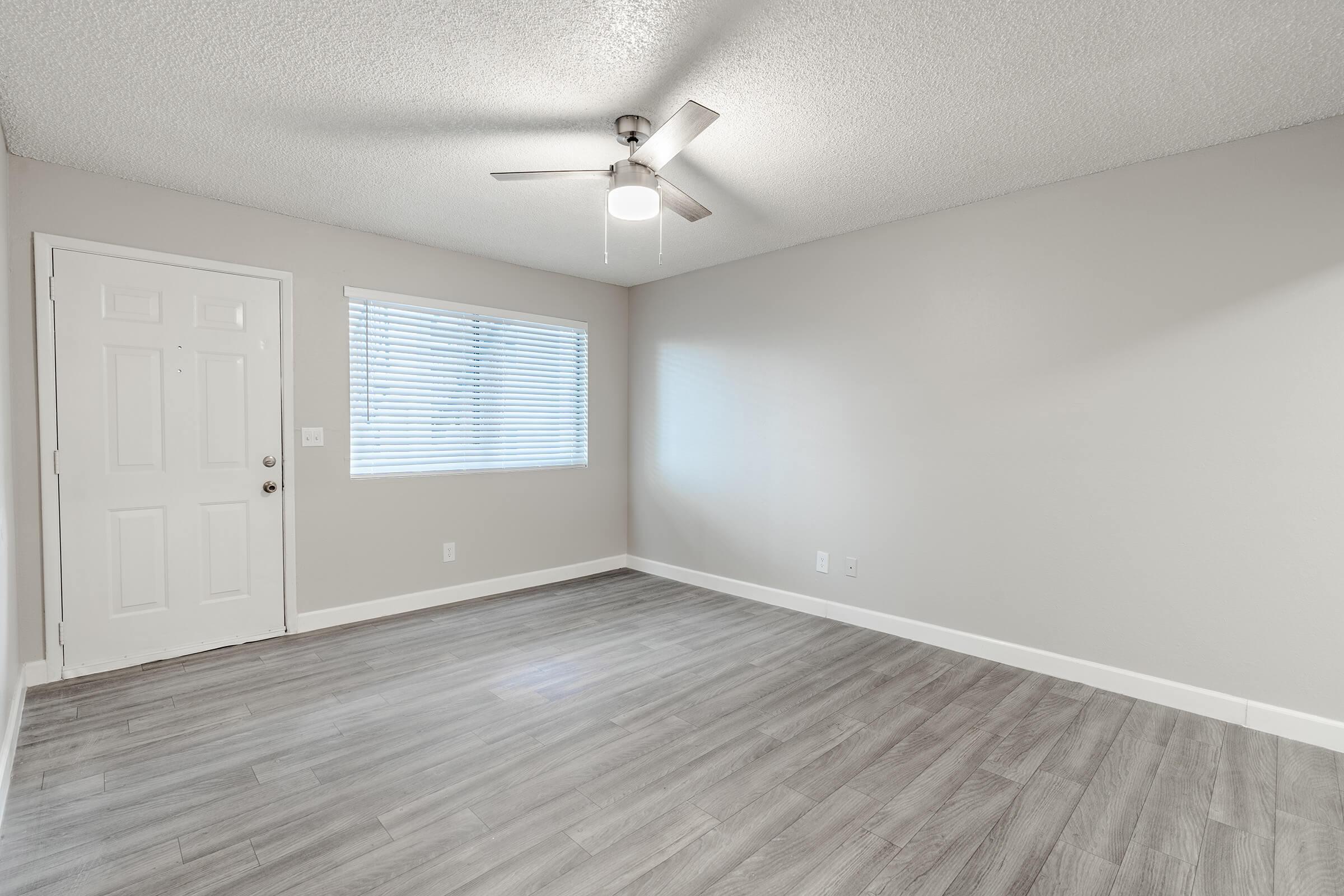 Living room with a ceiling fan and window next to front door entry way