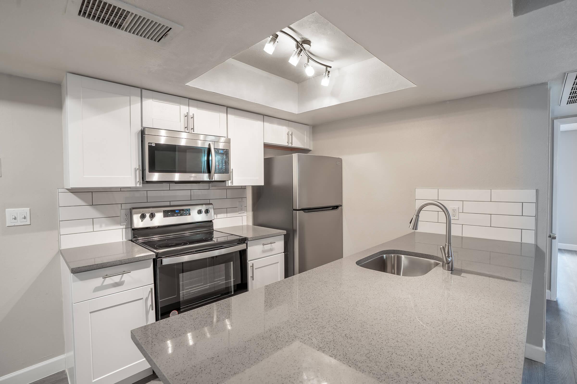 Brand new modern renovated kitchen with grey quartz countertops and white shaker cabinets