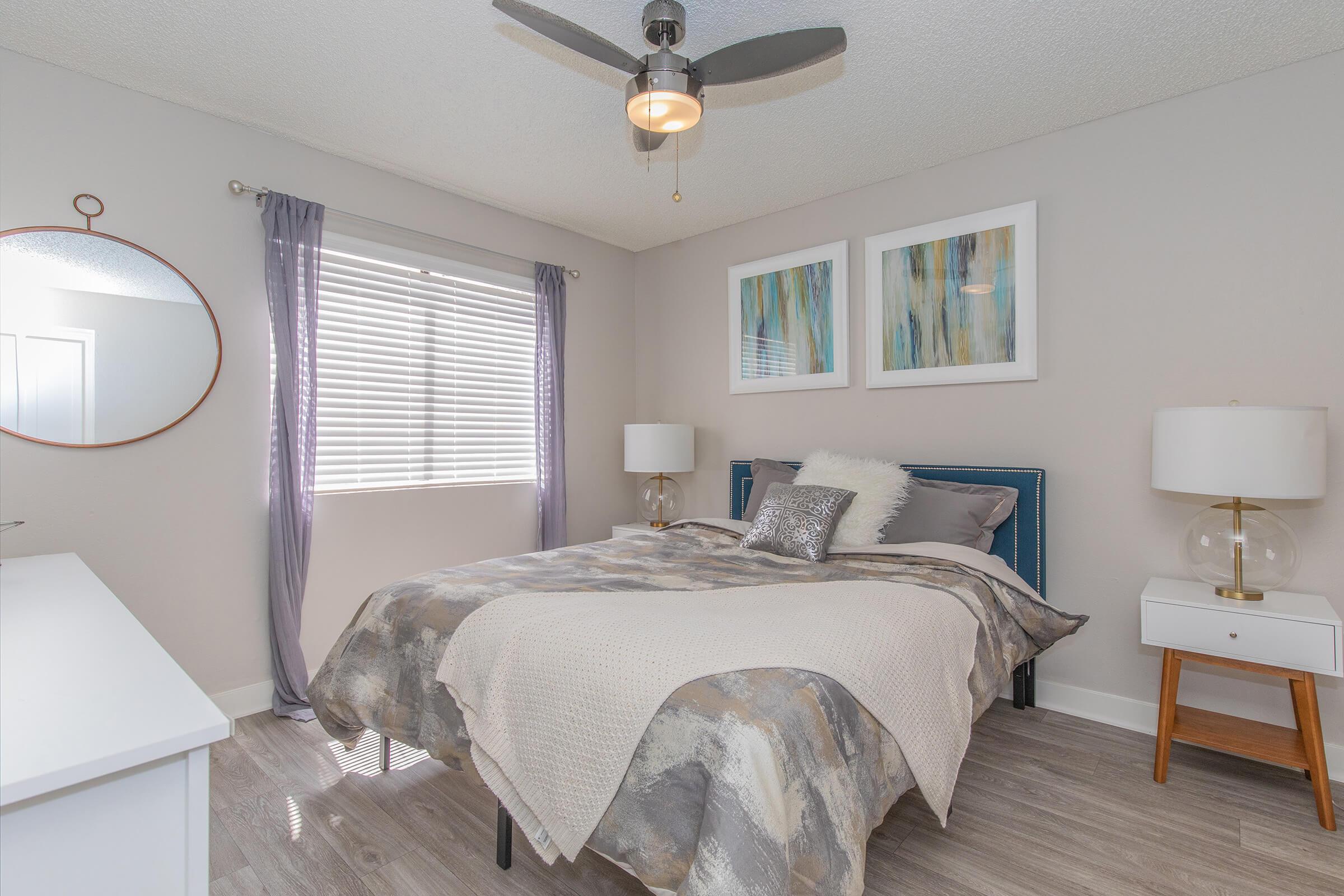 Spacious bedroom with large window and ceiling fan