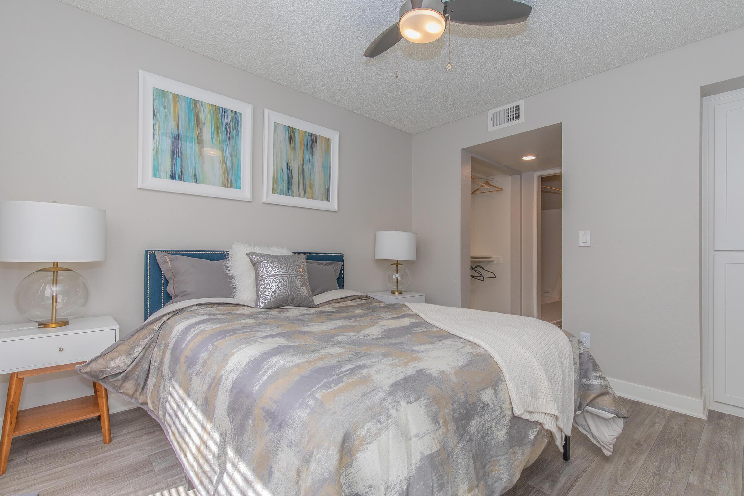 Bedroom set in modern spacious room with a ceiling fan and attached closet and bathroom space