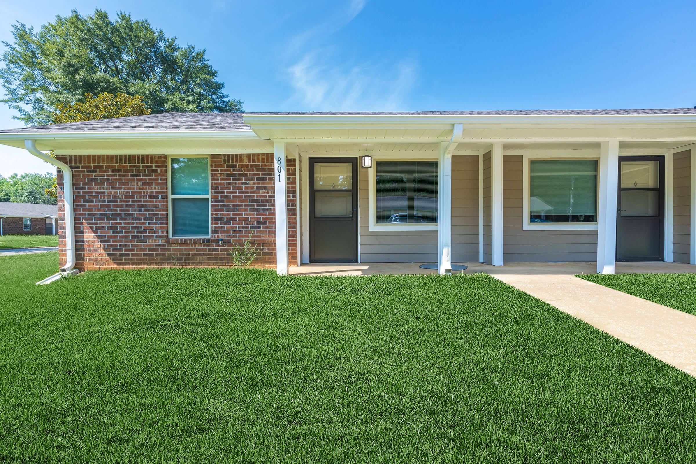 a large brick building with green grass in front of a house