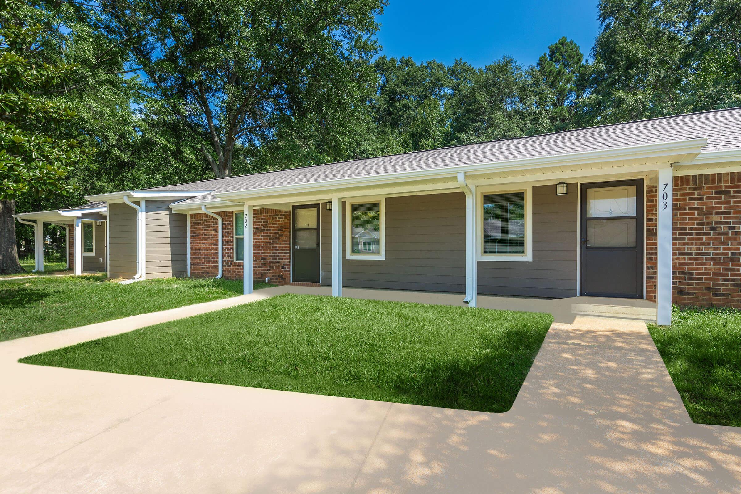 a house with a lawn in front of a brick building