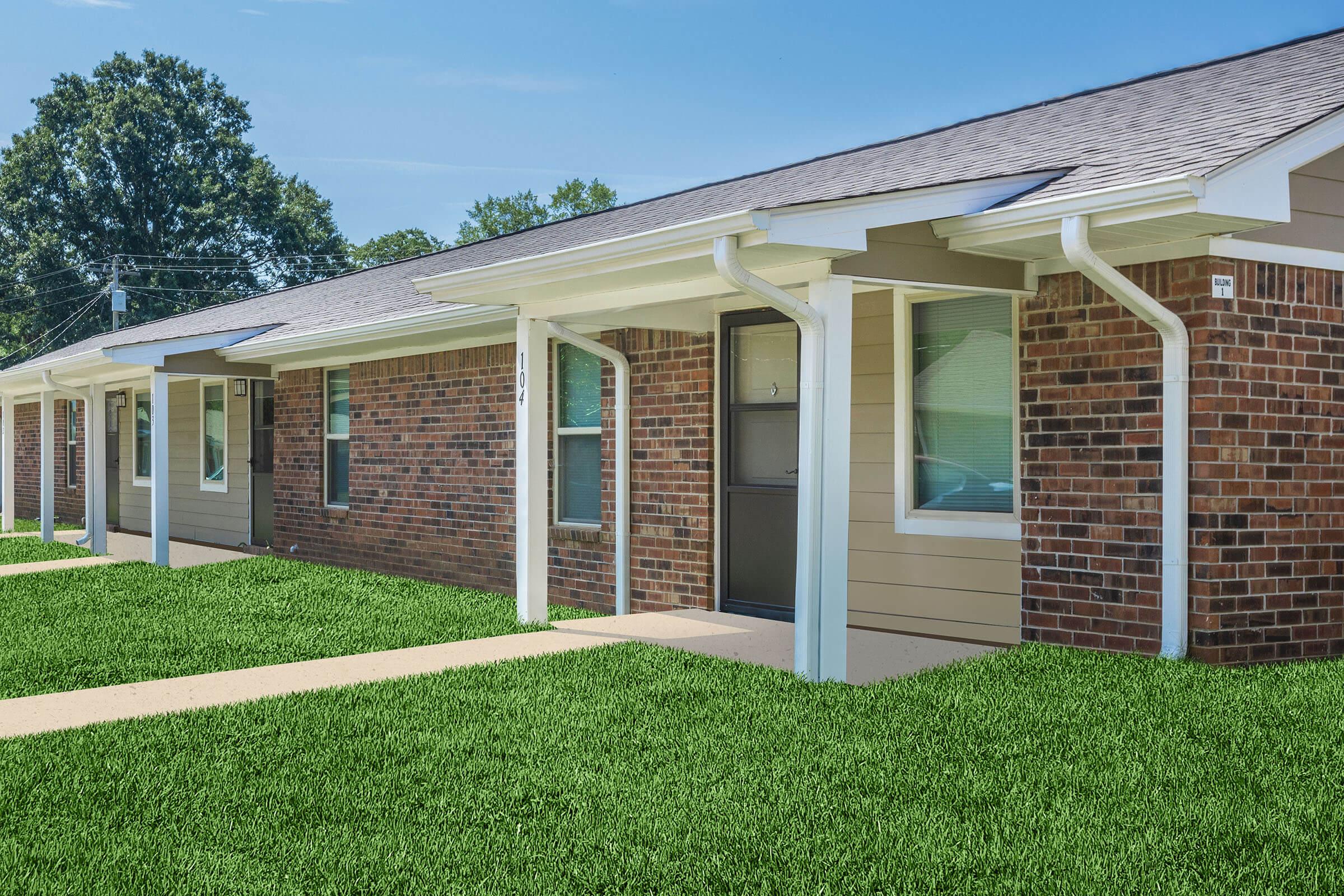 a large brick building with green grass in front of a house